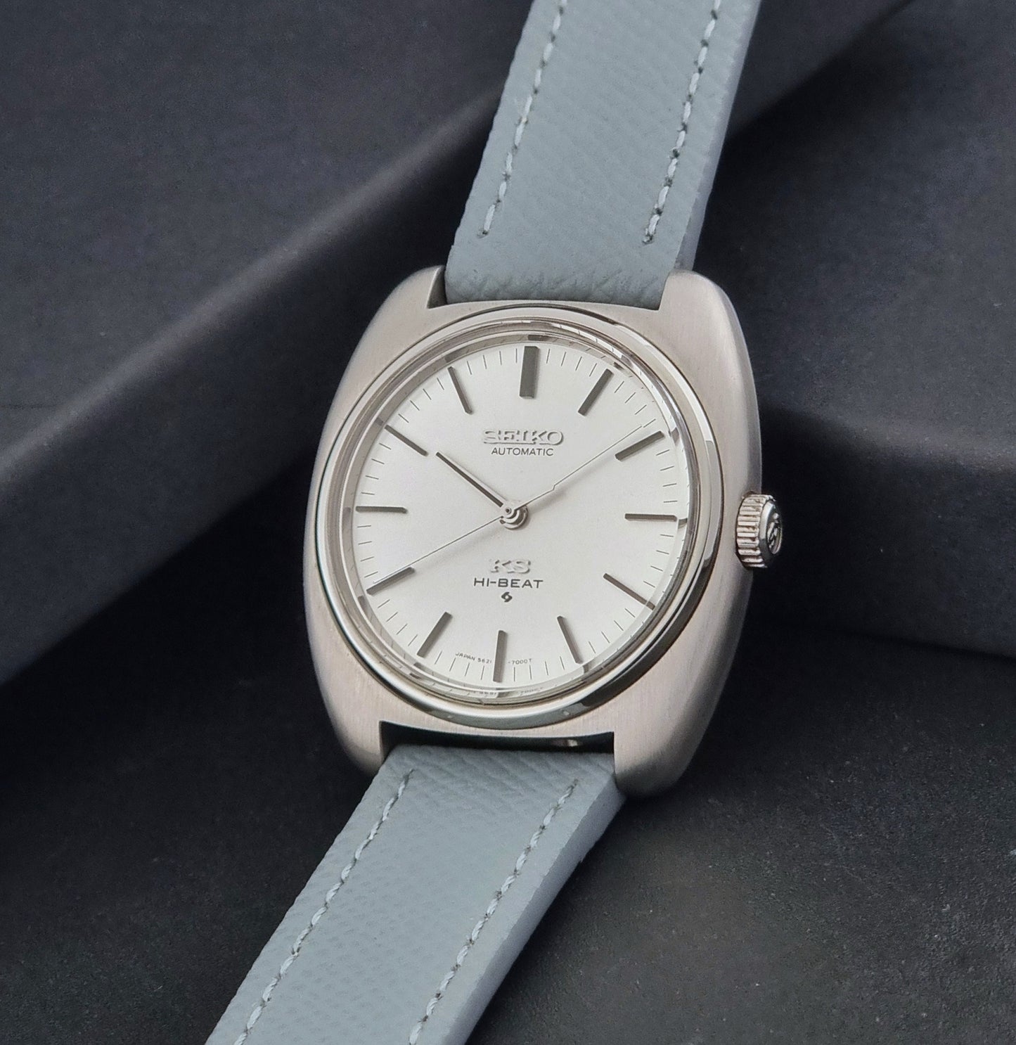 Vintage King Seiko Wristwatch 5621-7000 with light grey leather strap on a dark gray background crown view
