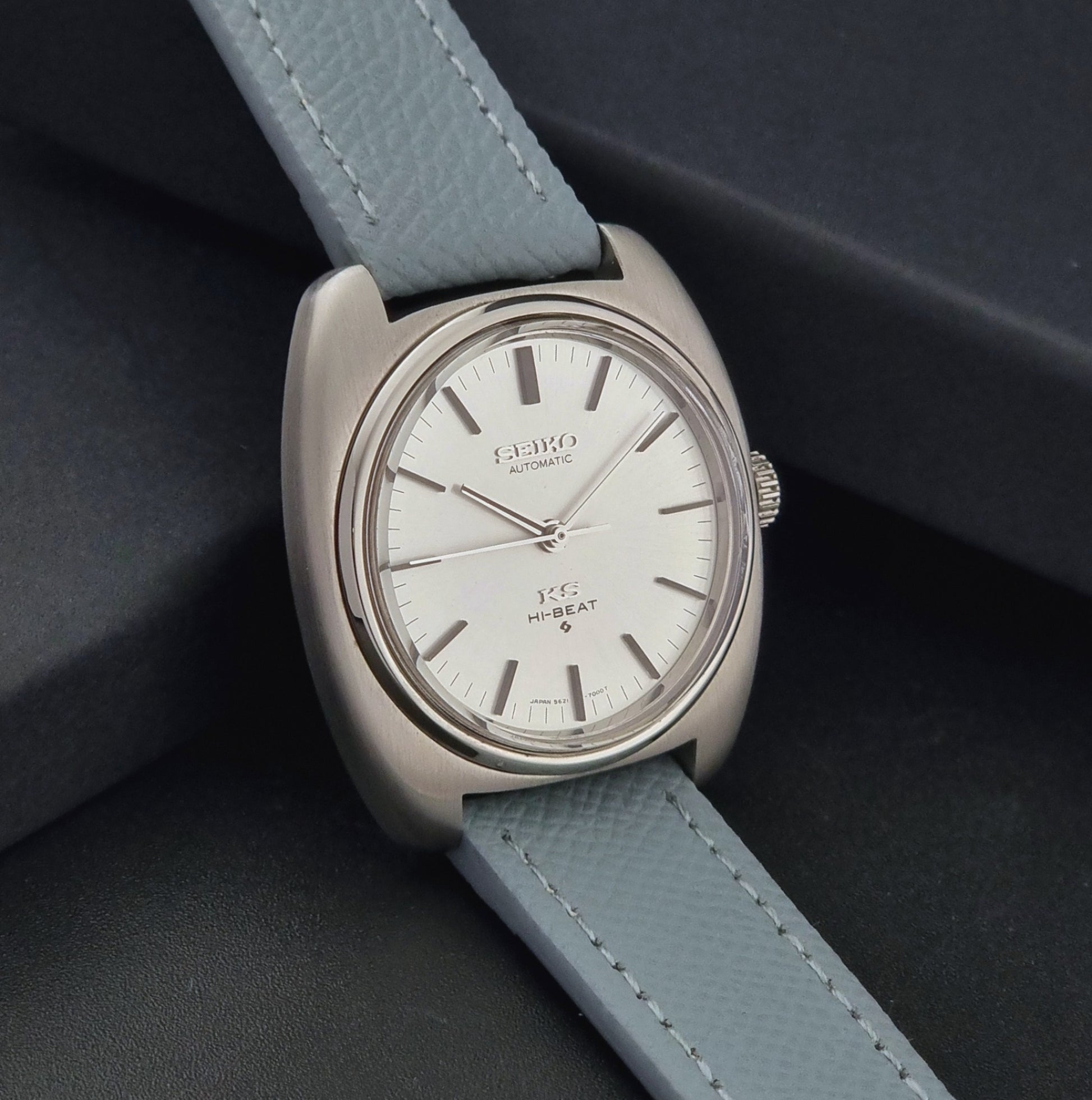 Vintage King Seiko Wristwatch 5621-7000 with light grey leather strap on a dark gray background side view