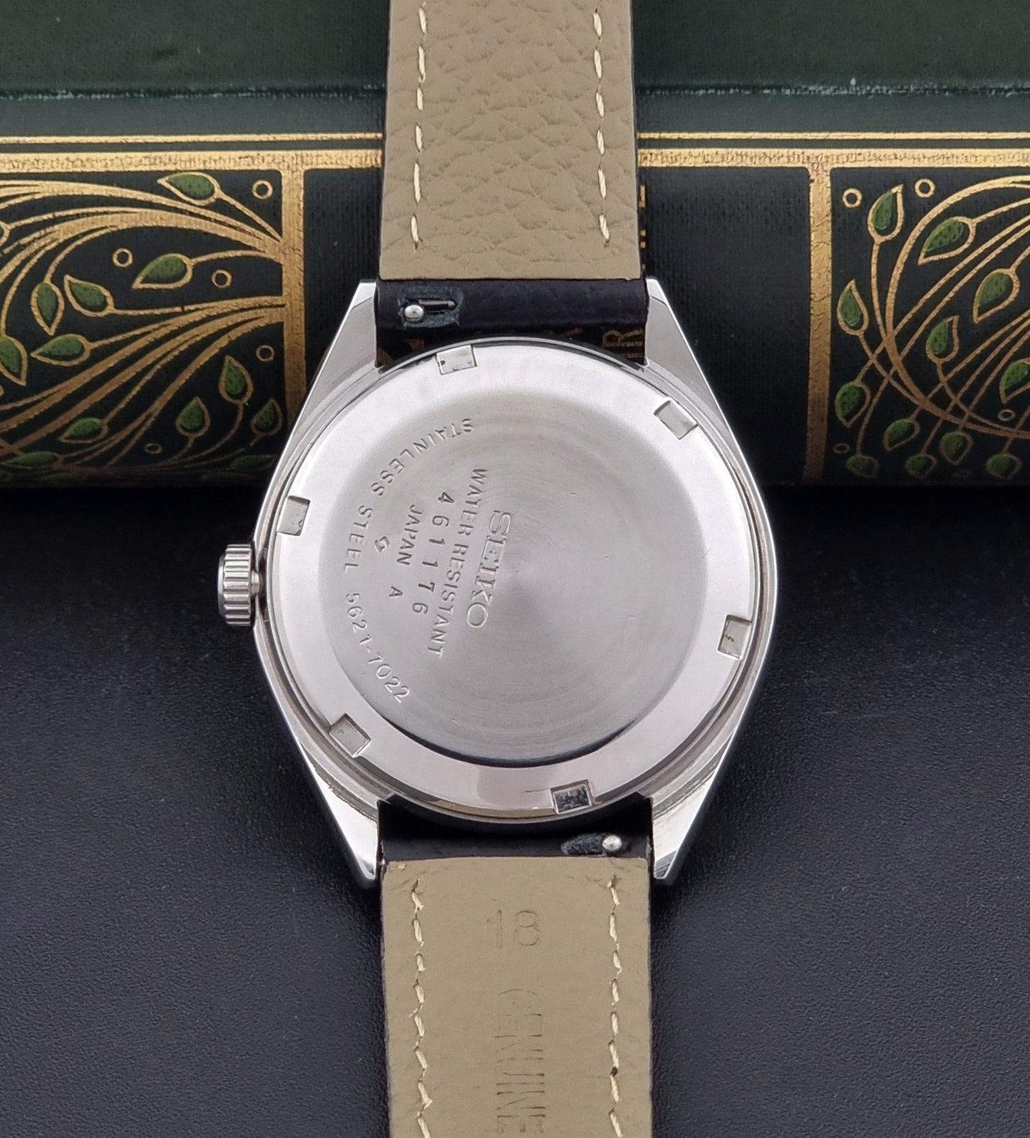 Vintage King Seiko Wristwatch 5621-7022 with a dark leather strap on a green background case back view