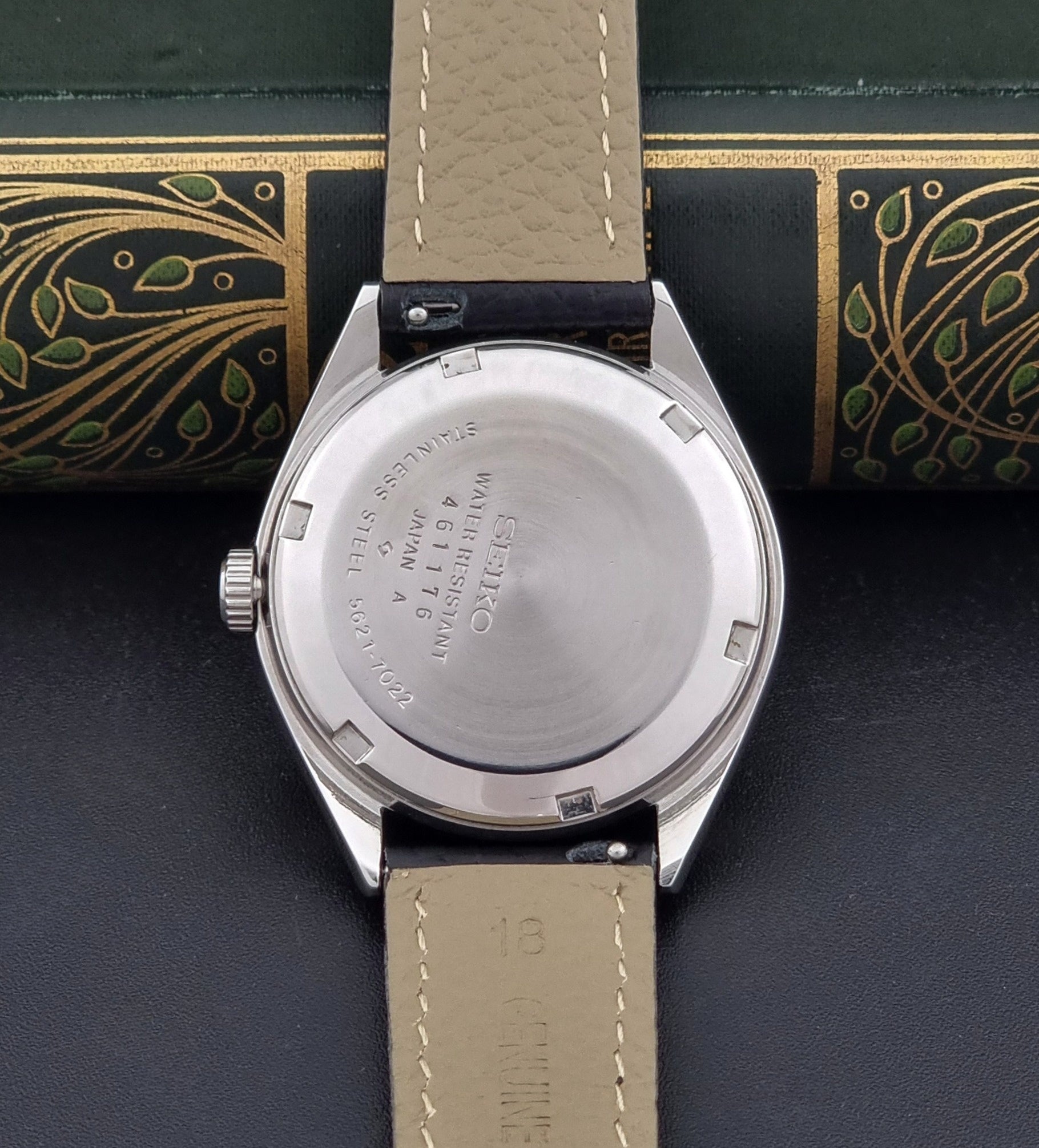 Vintage King Seiko Wristwatch 5621-7022 with a dark leather strap on a green background case back view