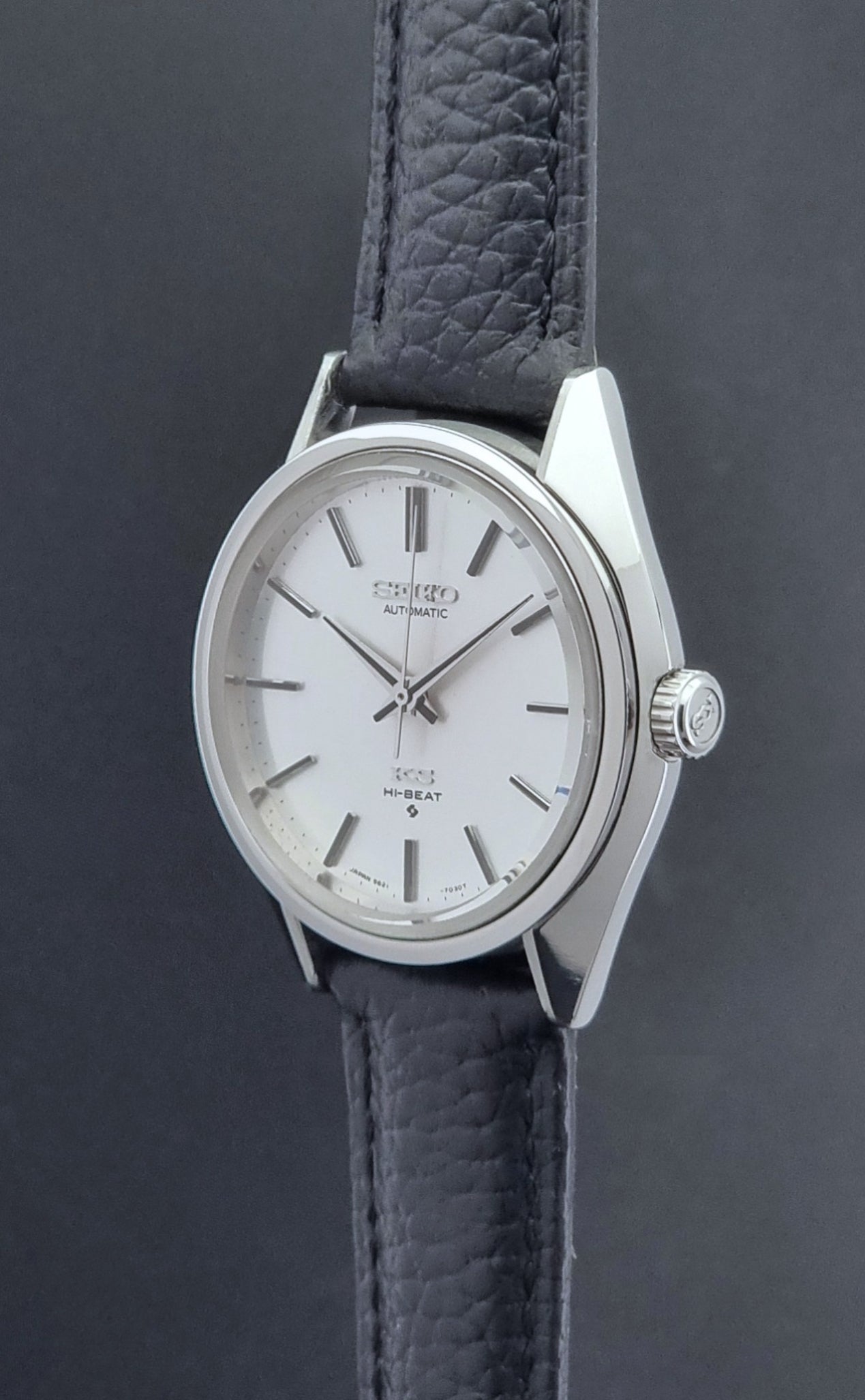 Vintage King Seiko Wristwatch 5621-7022 with a dark leather strap on a green background crown profile view