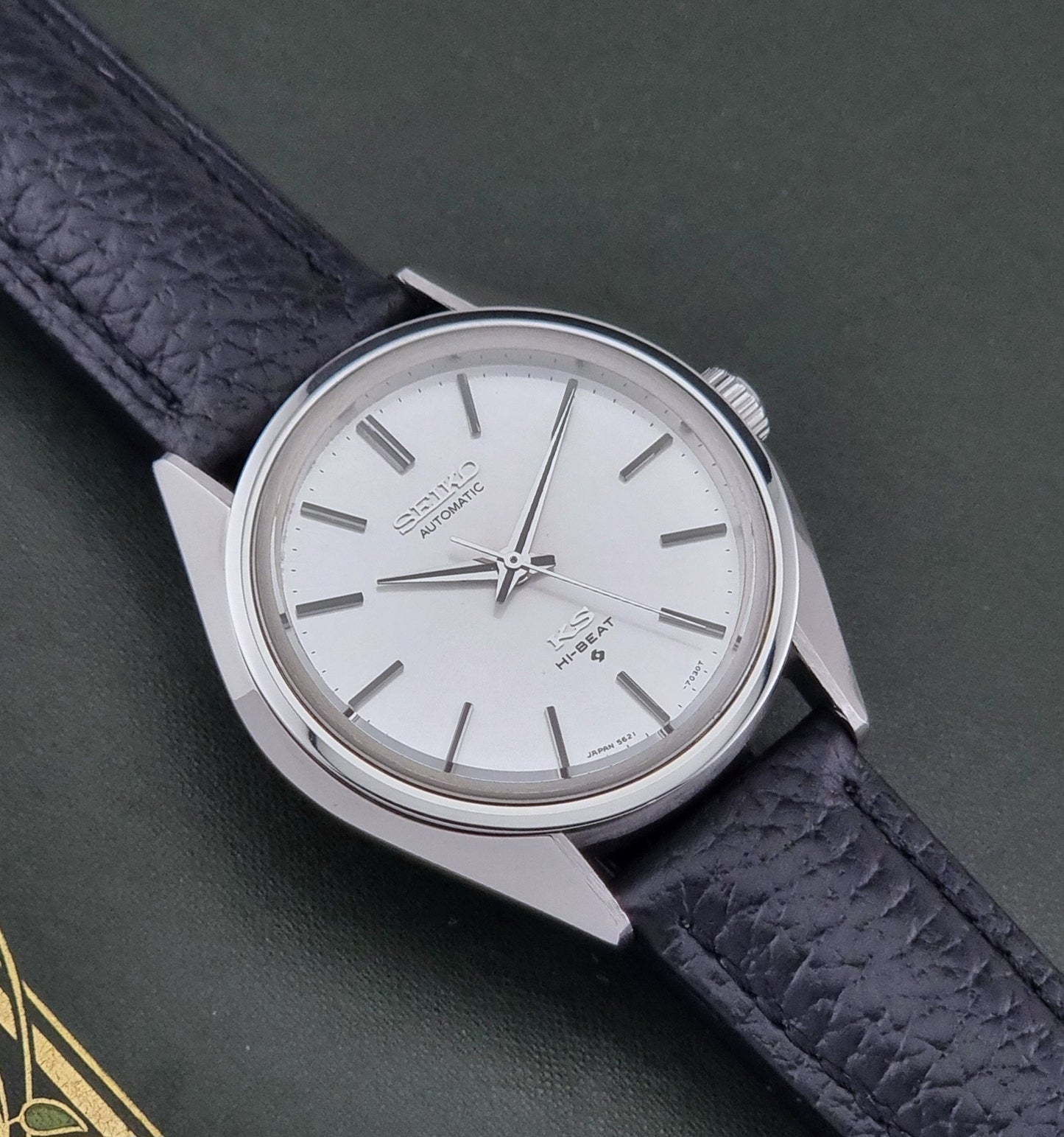 Vintage King Seiko Wristwatch 5621-7022 with a dark leather strap on a green background close up dial view