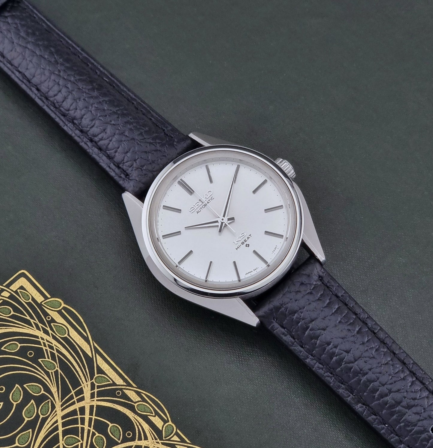 Vintage King Seiko Wristwatch 5621-7022 with a dark leather strap on a green background dial