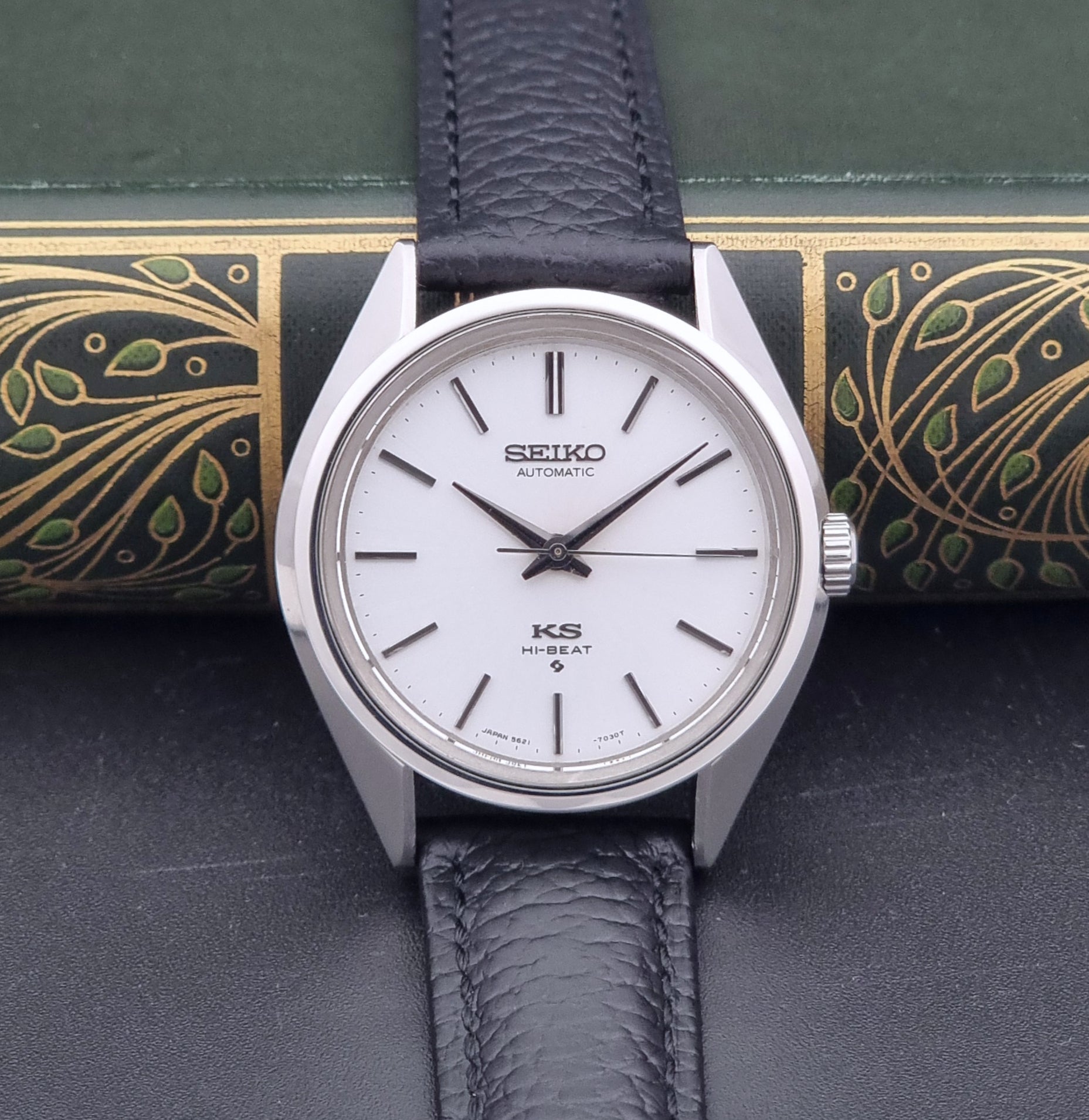 Vintage King Seiko Wristwatch 5621-7022 with a dark leather strap on a green background dial view