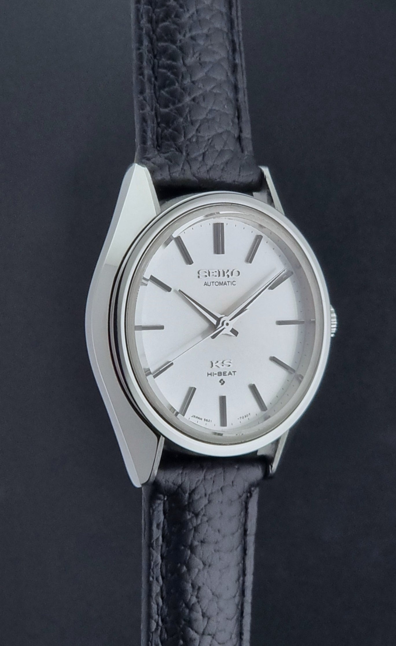 Vintage King Seiko Wristwatch 5621-7022 with a dark leather strap on a green background side profile view