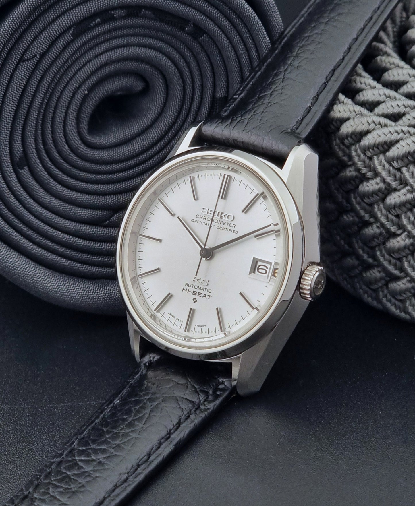 Vintage King Seiko 5625-7040 wrist watch with a black leather strap on a textured dark background crown view