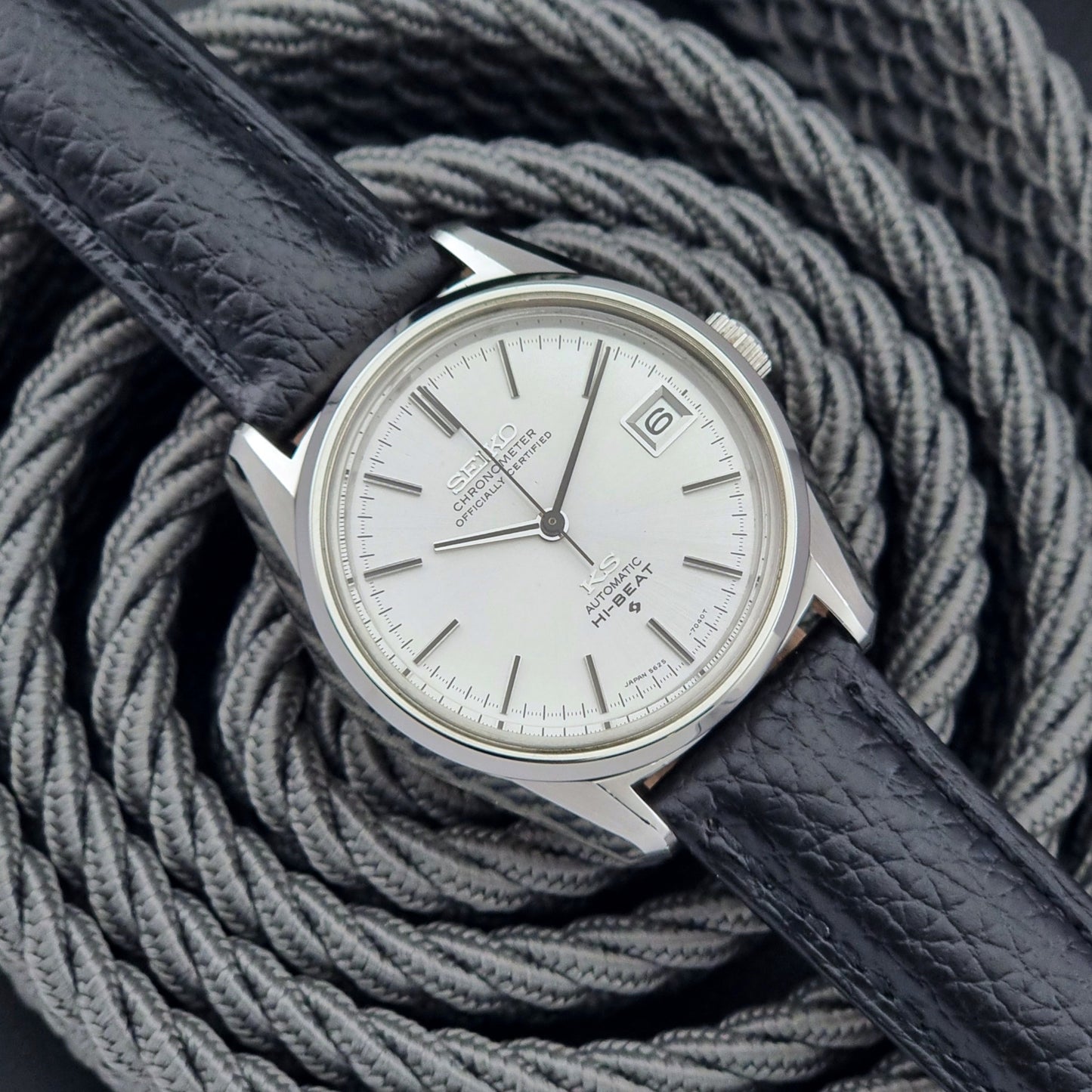 Vintage King Seiko 5625-7040 wrist watch with a black leather strap on a textured dark background front