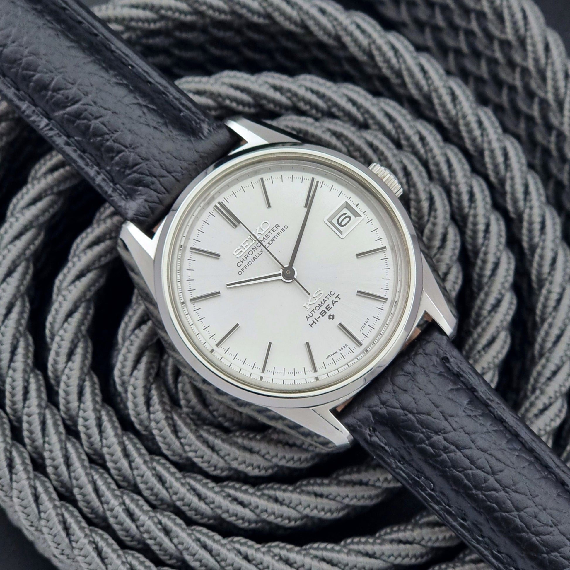 Vintage King Seiko 5625-7040 wrist watch with a black leather strap on a textured dark background front