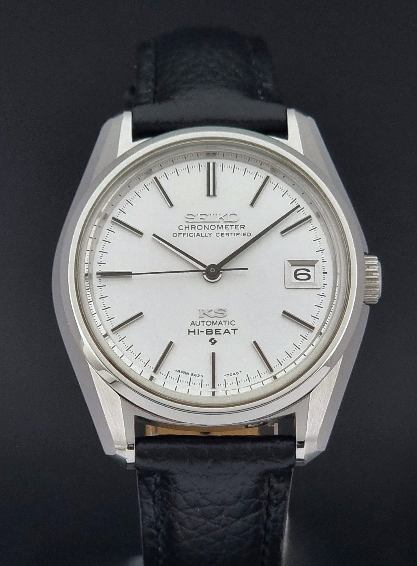 Vintage King Seiko 5625-7040 wrist watch with a black leather strap on a textured dark background close front view