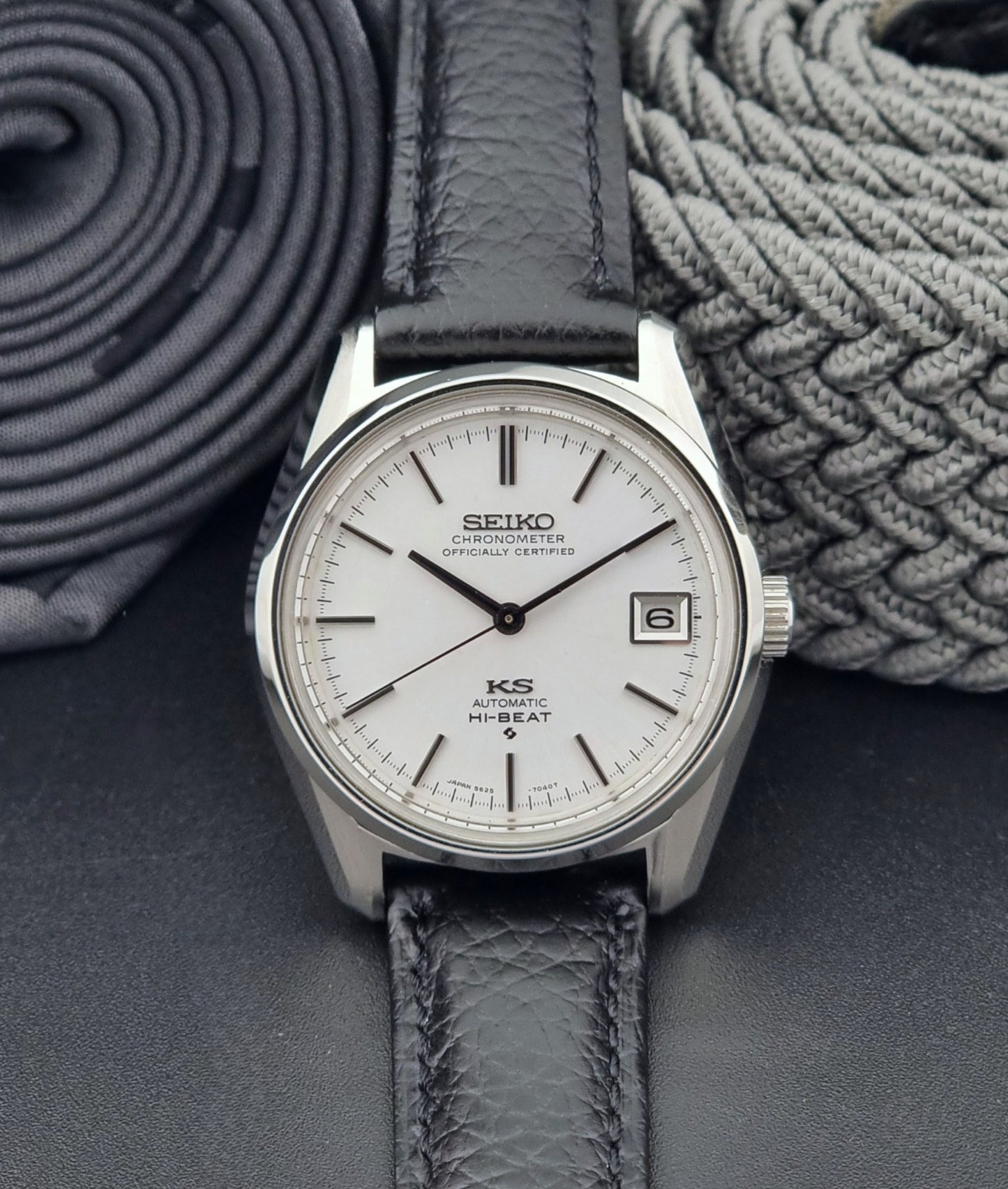 Vintage King Seiko 5625-7040 wrist watch with a black leather strap on a textured dark background front view