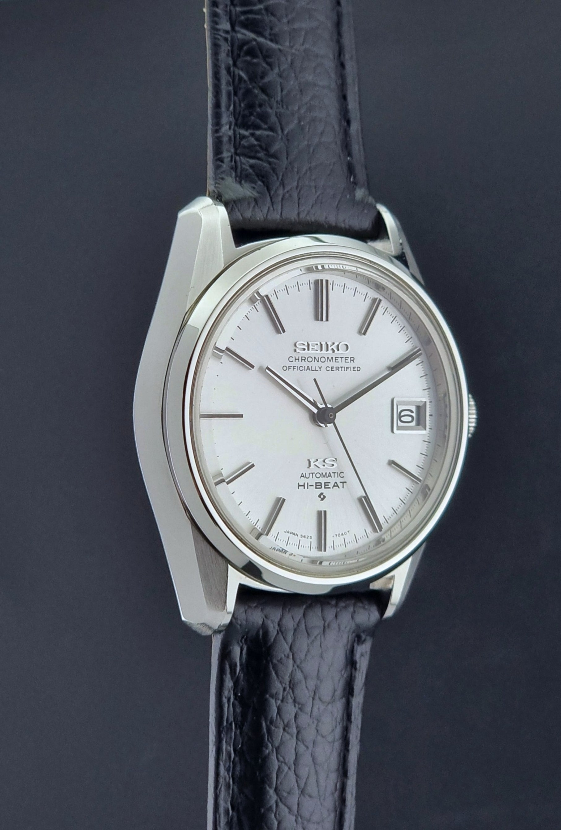 Vintage King Seiko 5625-7040 wrist watch with a black leather strap on a textured dark background side profile view