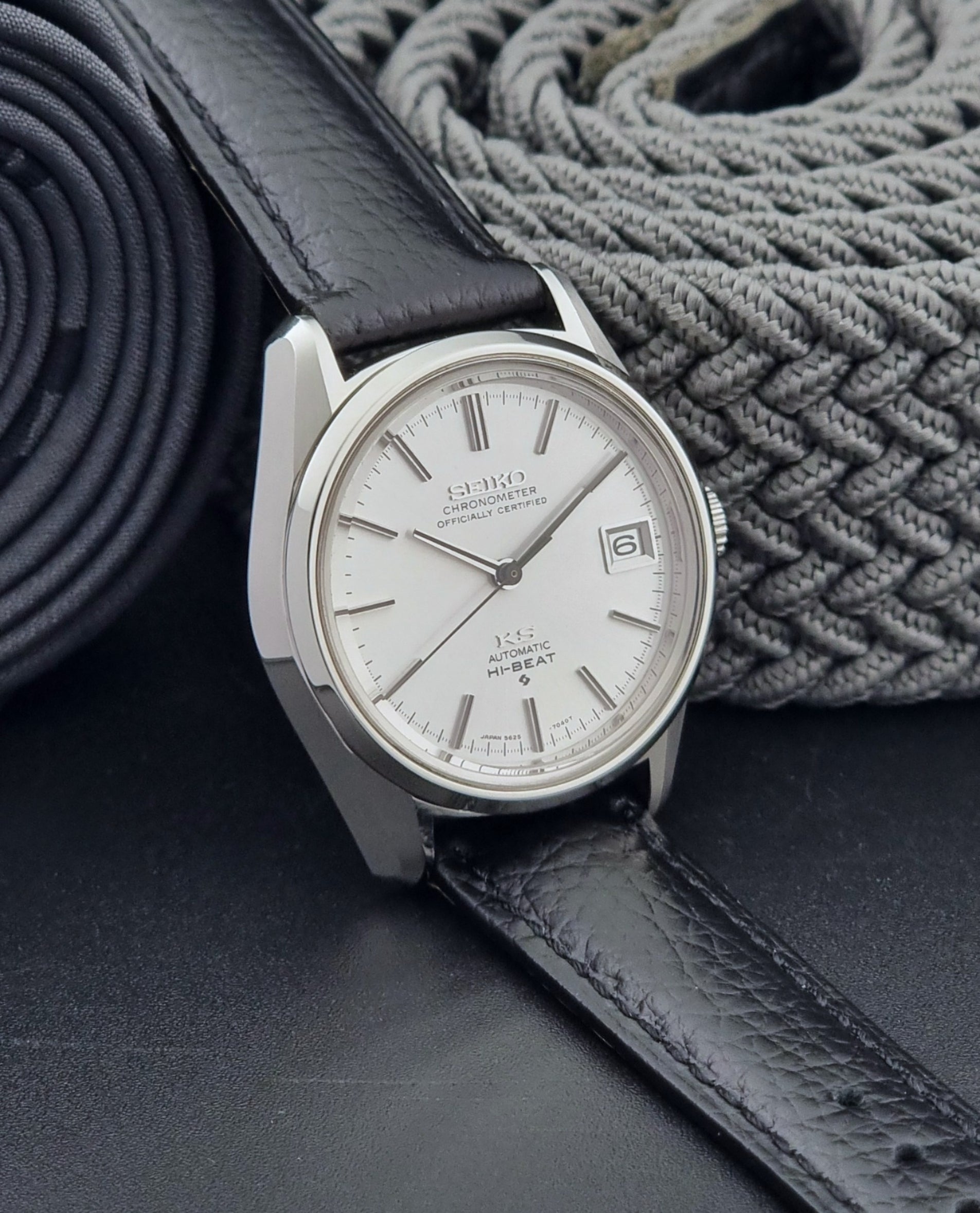 Vintage King Seiko 5625-7040 wrist watch with a black leather strap on a textured dark background side view