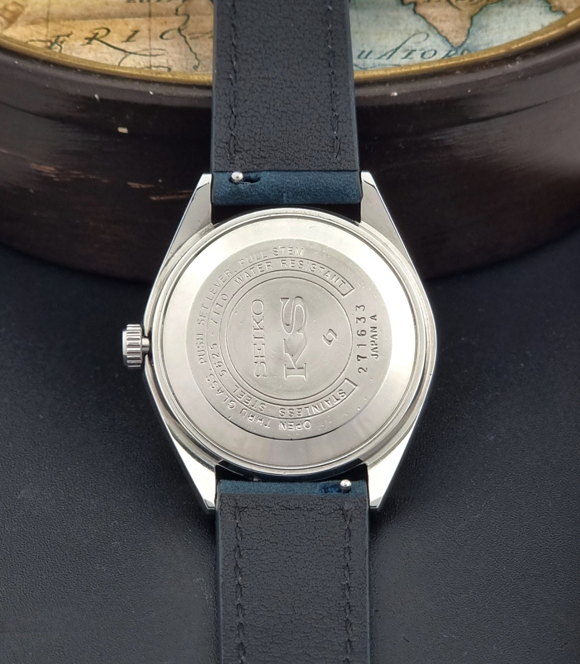 Vintage King Seiko Wristwatch 5625-7110 blue strap and silver case on a dark surface case back view