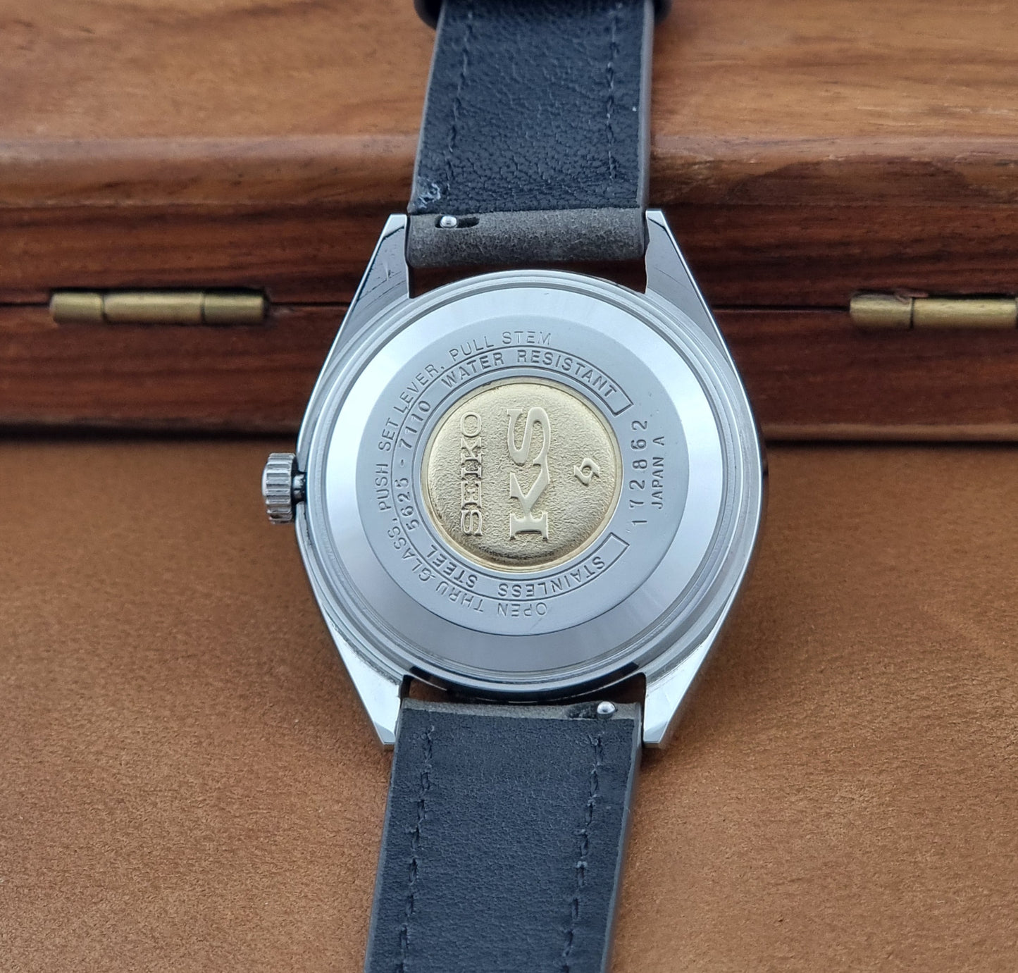 Vintage King Seiko 5625-7110 Wristwatch with a gray strap and white dial on a brown background case back view