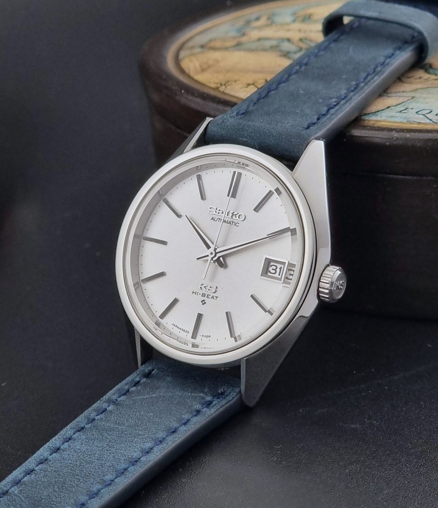 Vintage King Seiko Wristwatch 5625-7110 blue strap and silver case on a dark surface crown view