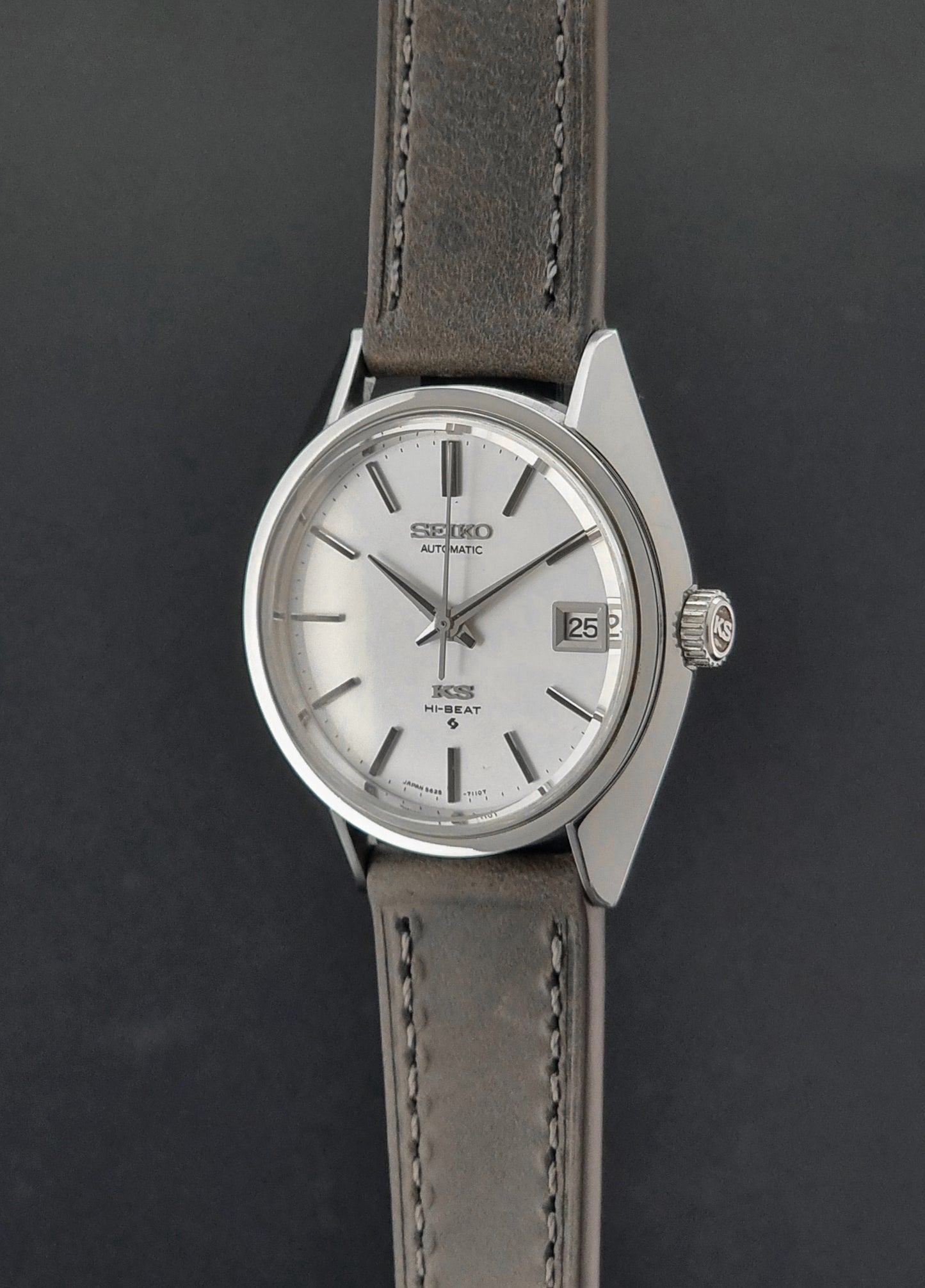 Vintage King Seiko 5625-7110 Wristwatch with a gray strap and white dial on a brown background crown profile view