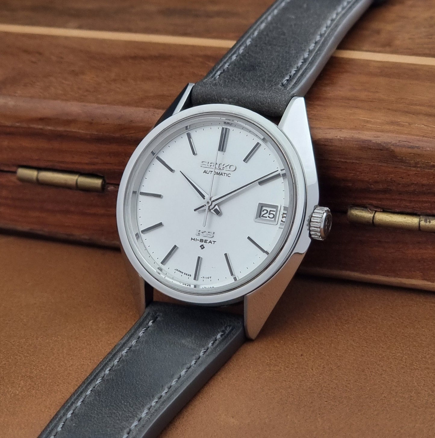 Vintage King Seiko 5625-7110 Wristwatch with a gray strap and white dial on a brown background crown view