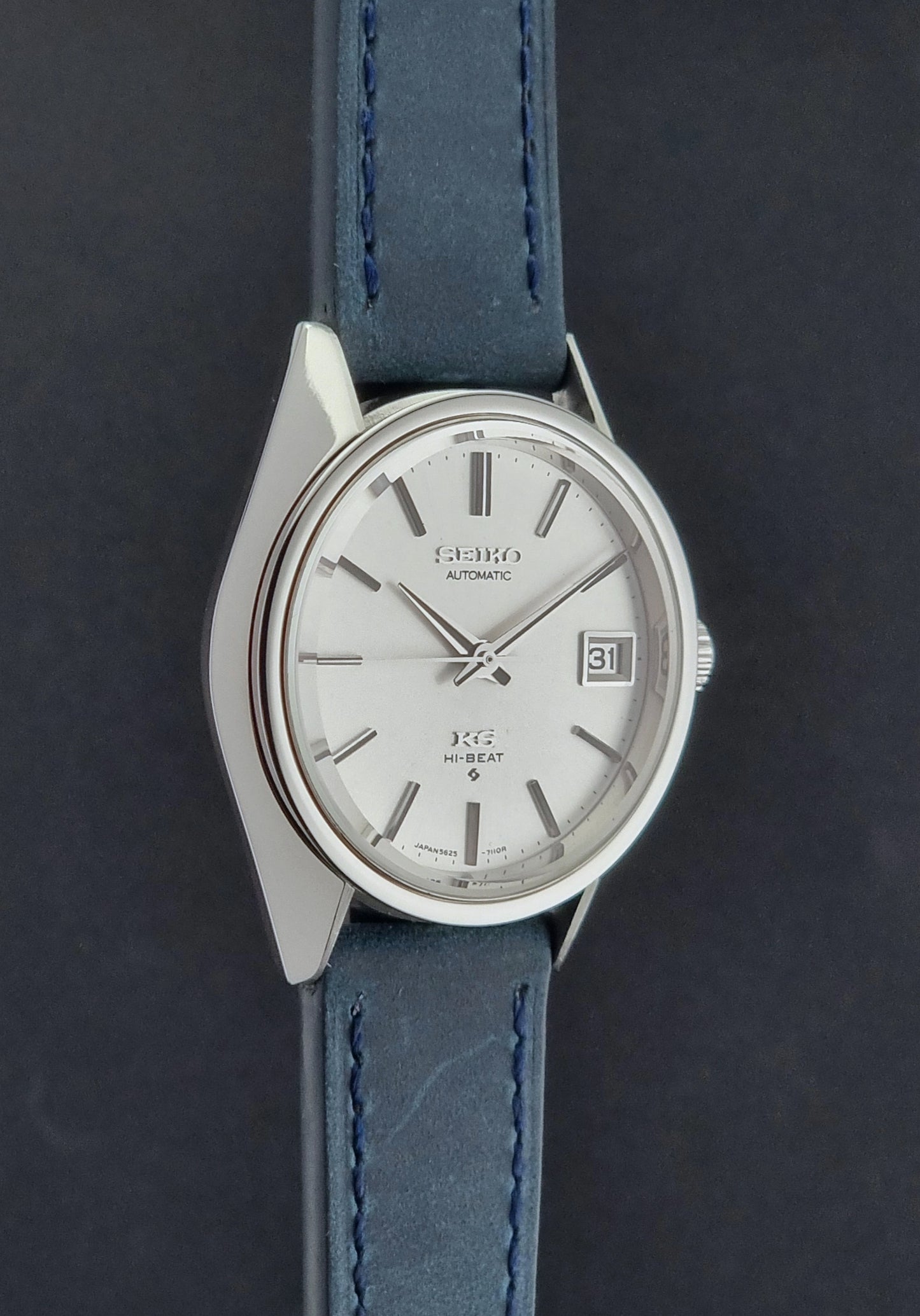 Vintage King Seiko Wristwatch 5625-7110 blue strap and silver case on a dark surface side profile view