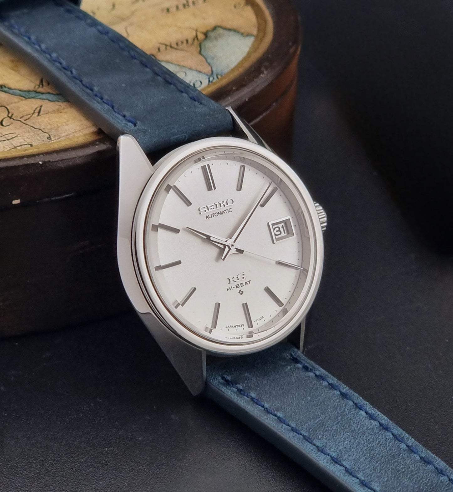 Vintage King Seiko Wristwatch 5625-7110 blue strap and silver case on a dark surface side view