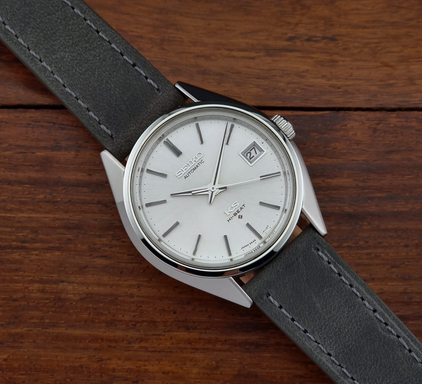 Vintage King Seiko watch with a silver case and black leather strap on a wooden surface
