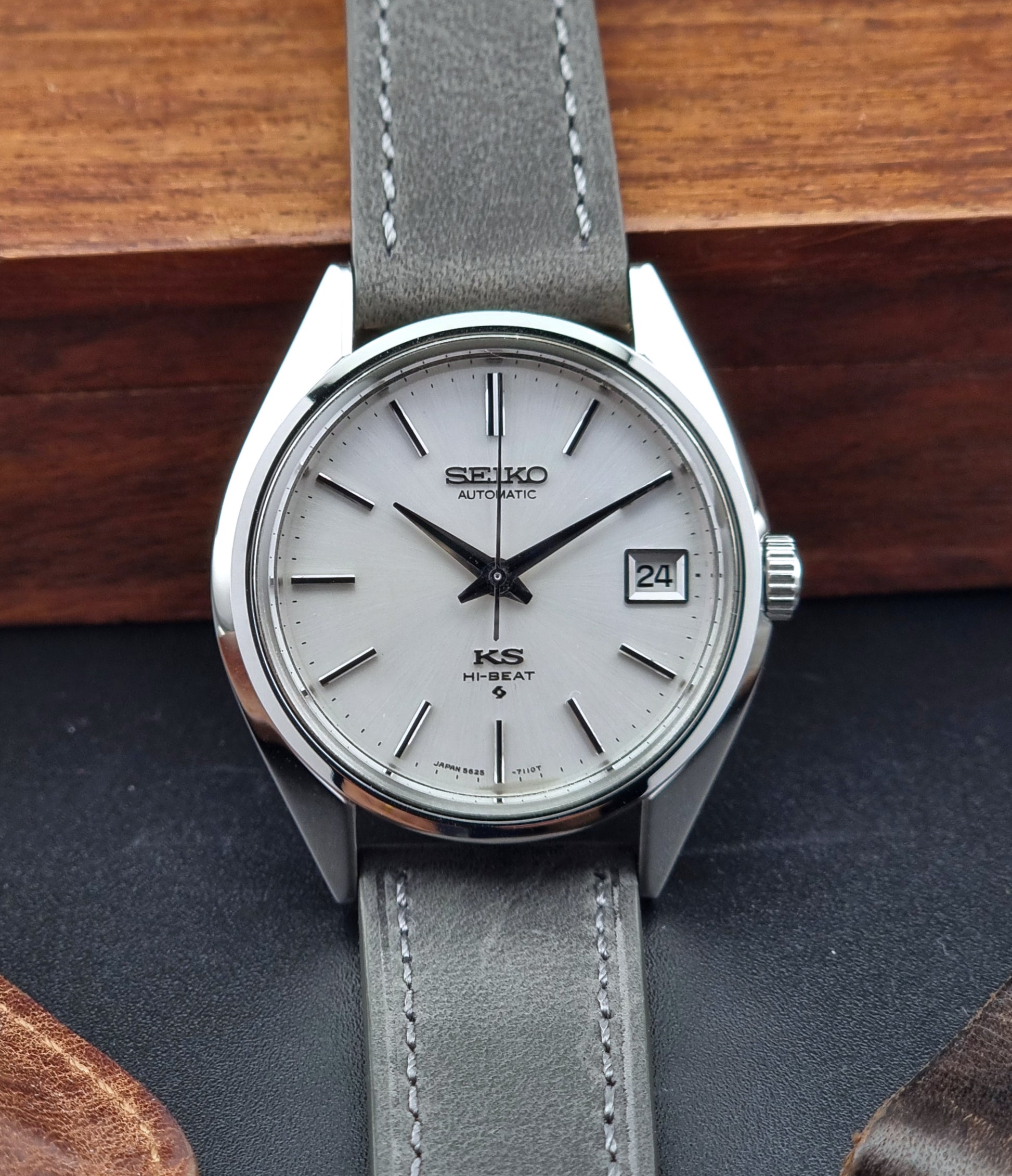 Vintage King Seiko watch with gray strap on a wooden surface