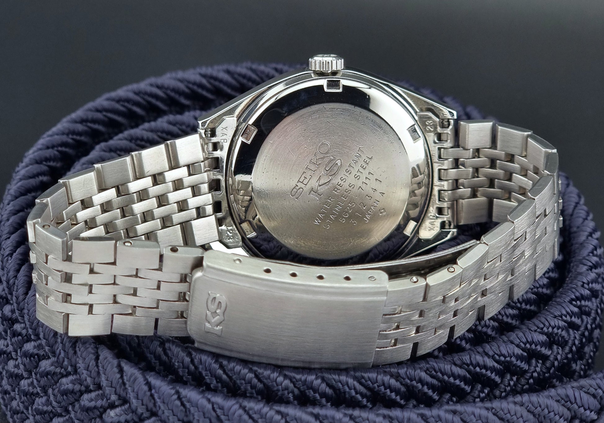 Silver watch with a textured band on a dark background