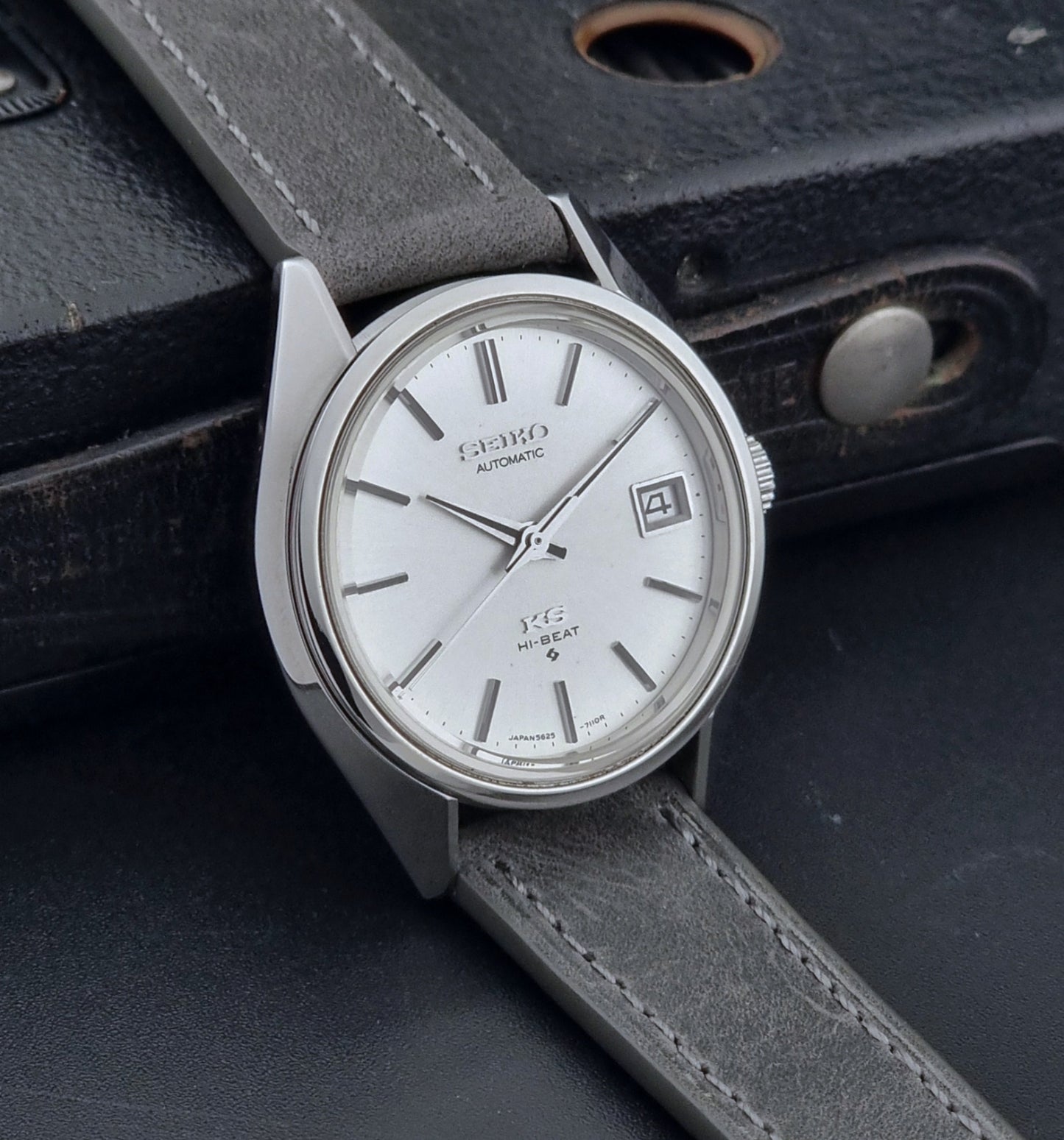 Vintage King Seiko Wristwatch 5625-7111 on a grey leather strap with a silver case and white dial on a dark background