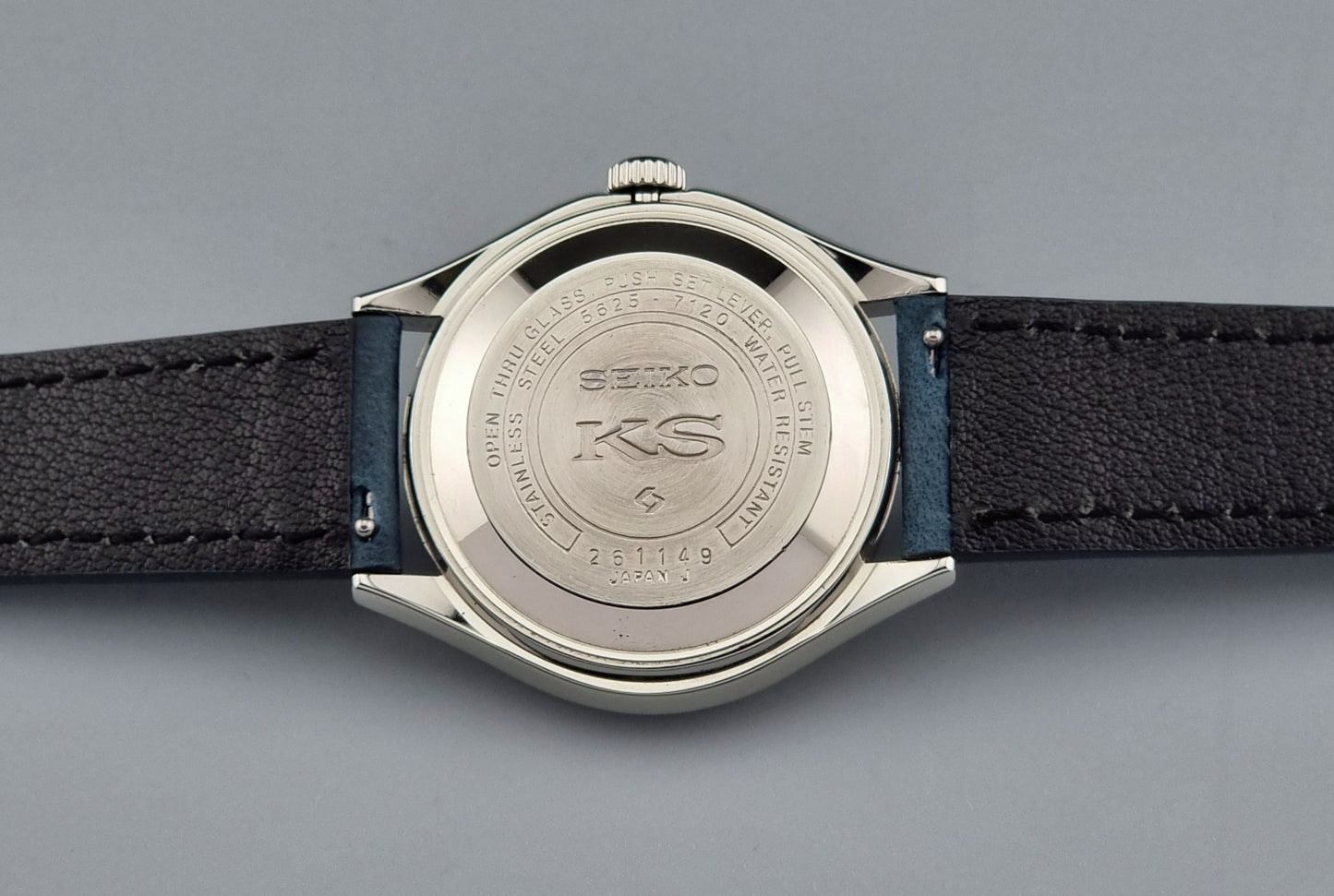 Close-up of a King Seiko watch case back on a grey background.