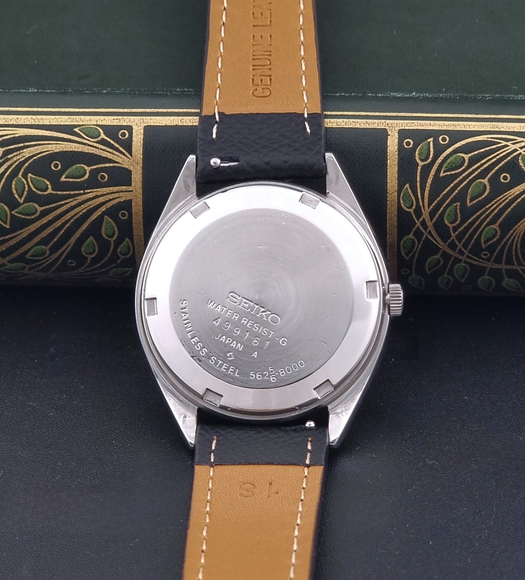 Vintage King Seiko Wristwatch 5625-8000 with a black leather strap on a dark background case back view