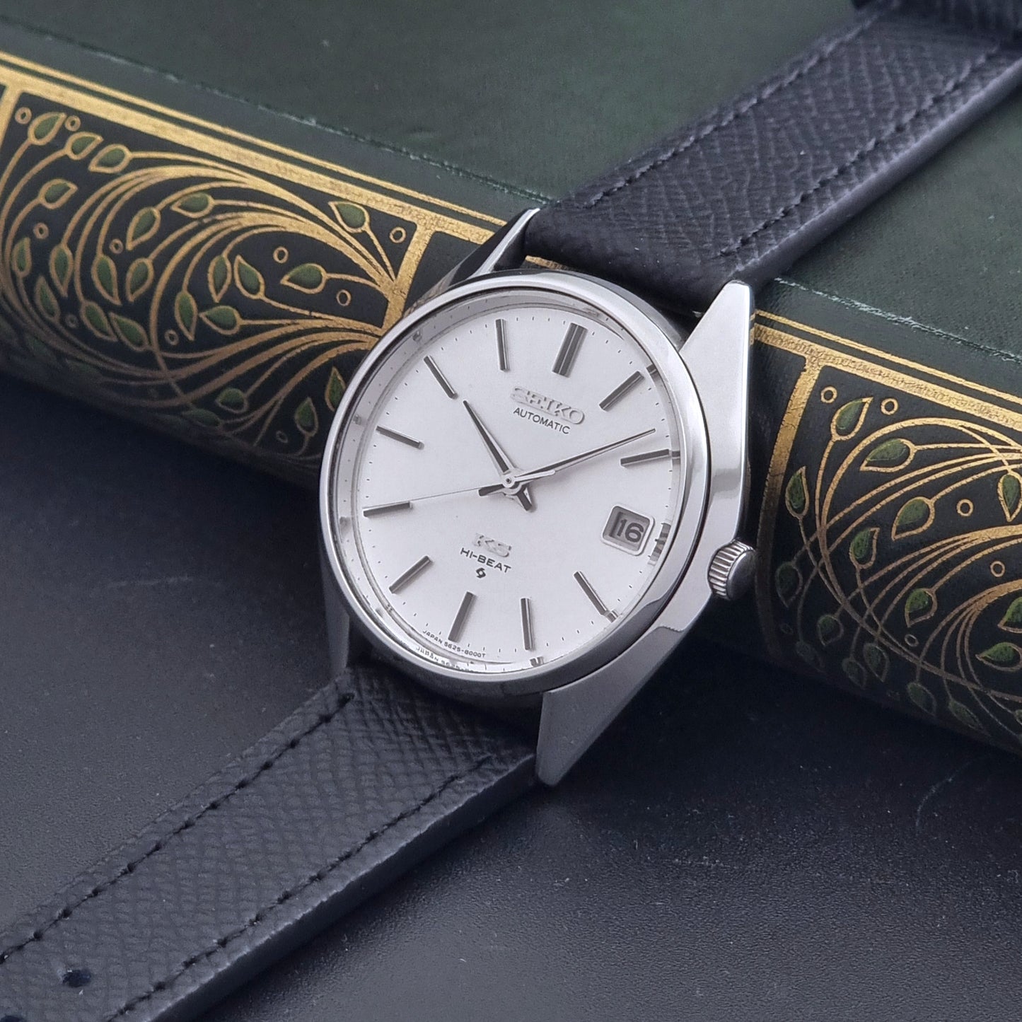 Vintage King Seiko Wristwatch 5625-8000 with a black leather strap on a dark background crown view