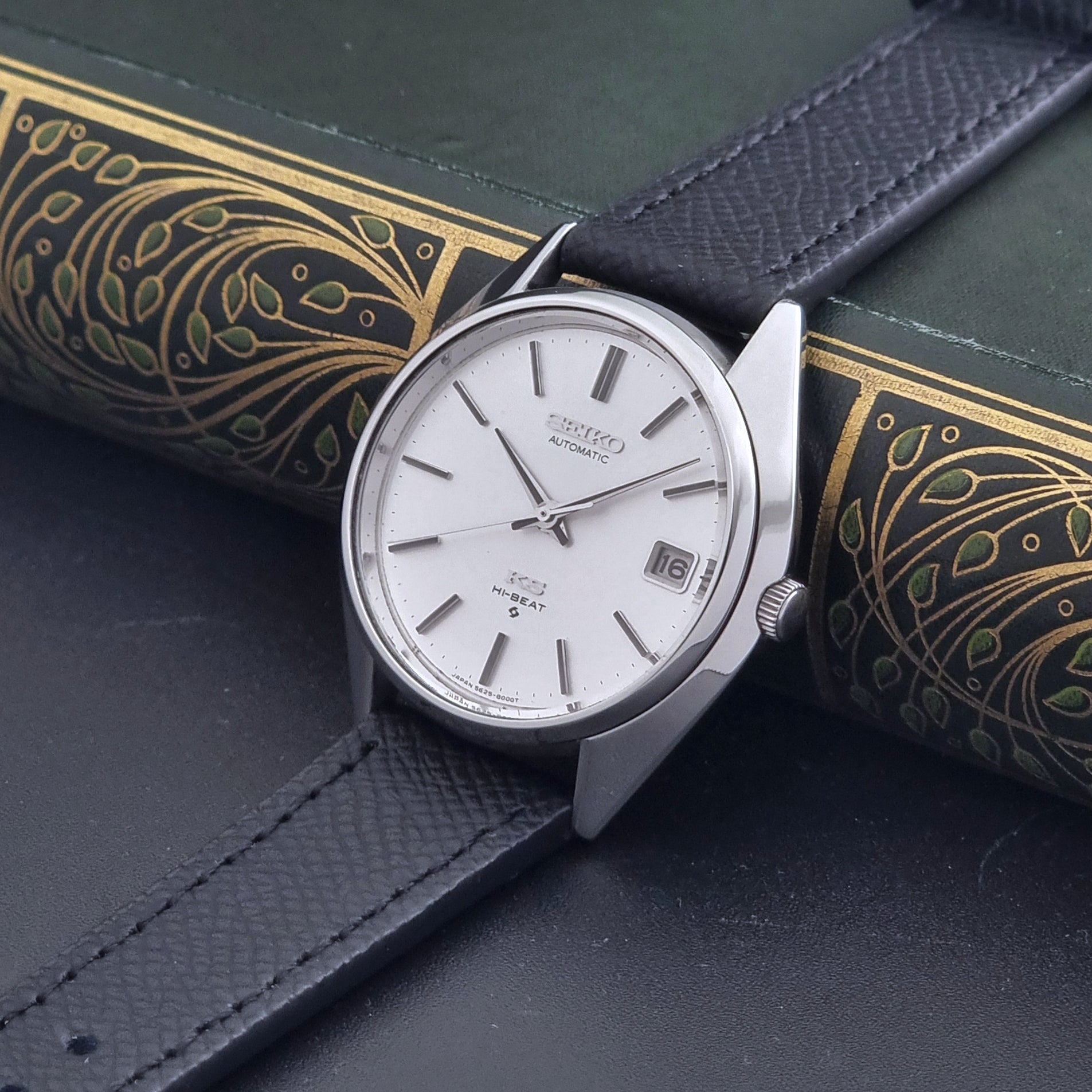 Vintage King Seiko Wristwatch 5625-8000 with a black leather strap on a dark background crown view