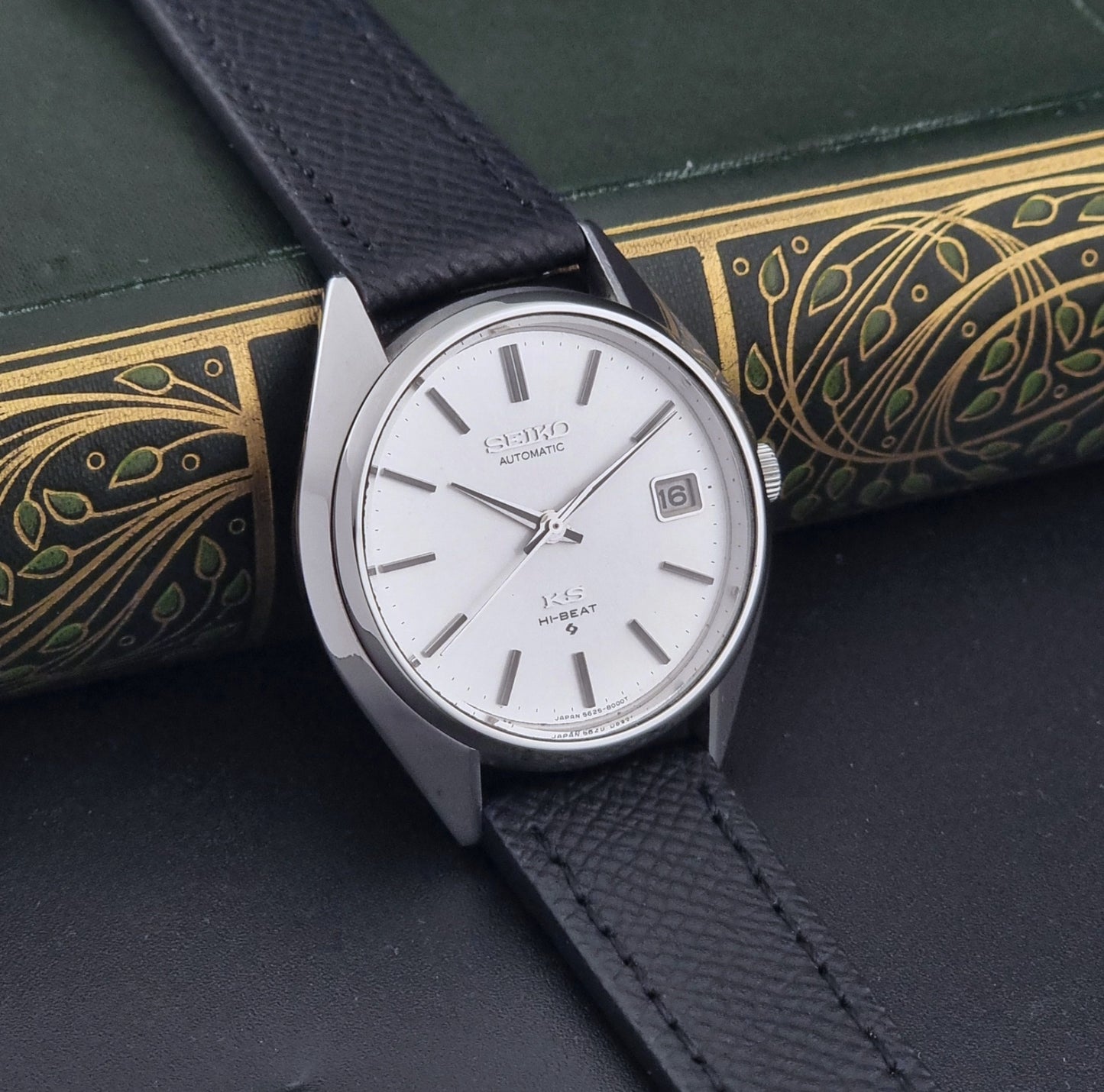 Vintage King Seiko Wristwatch 5625-8000 with a black leather strap on a dark background side view