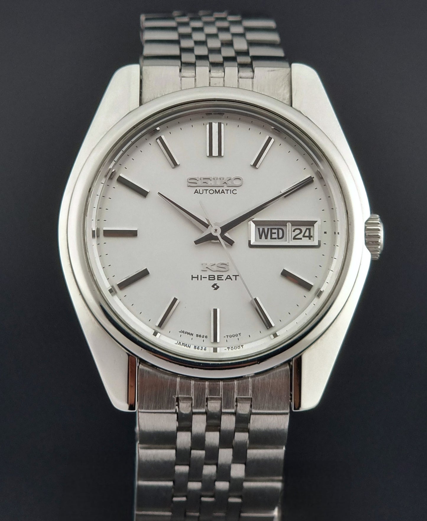 Silver Seiko watch with a white face on a dark background