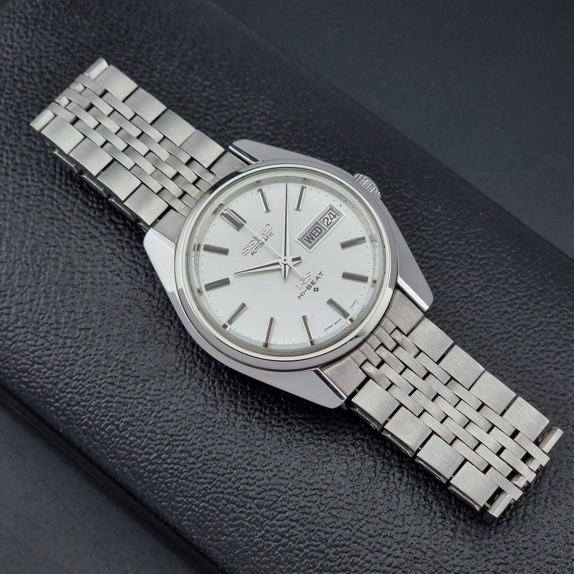 Vintage King Seiko watch with a metal bracelet on a dark textured surface
