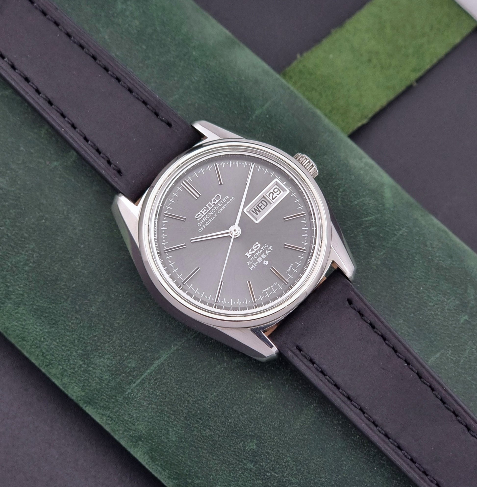 King Seiko watch 5626-7040 watch with black leather strap on a green and gray background