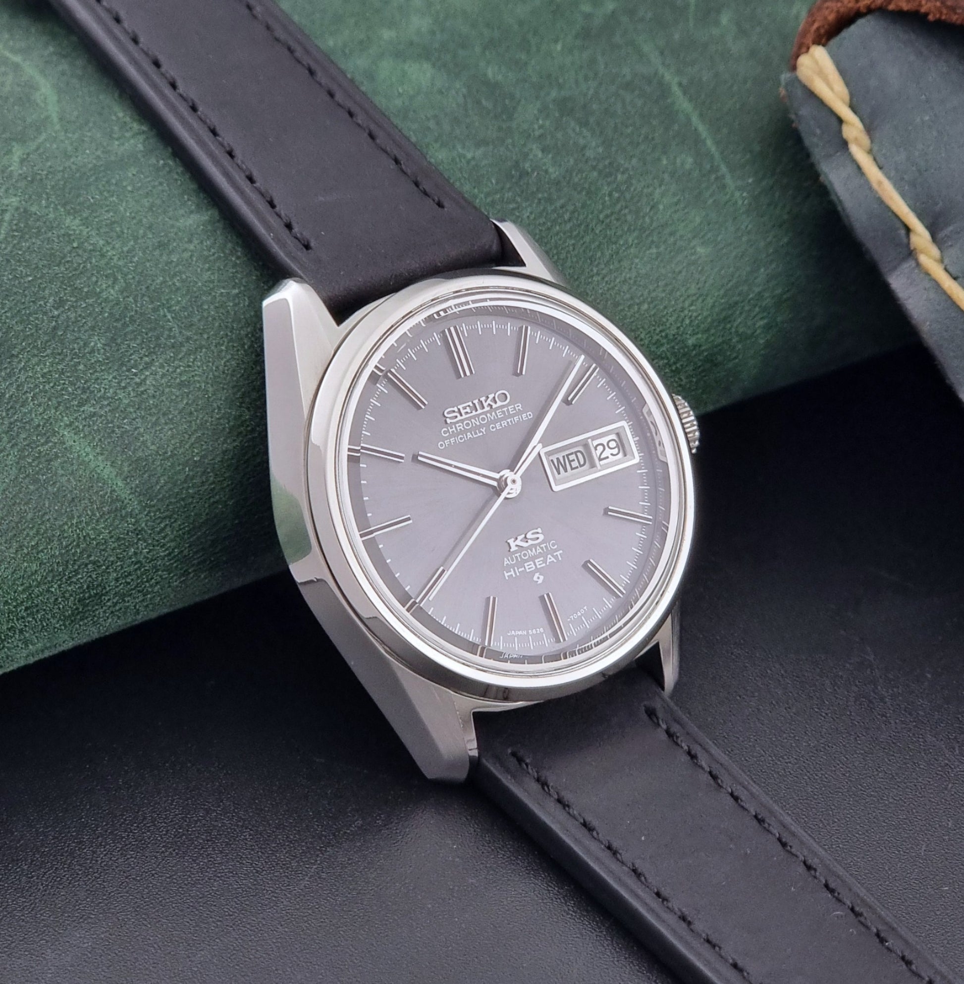 King Seiko watch 5626-7040 watch with black leather strap on a green and gray background side view