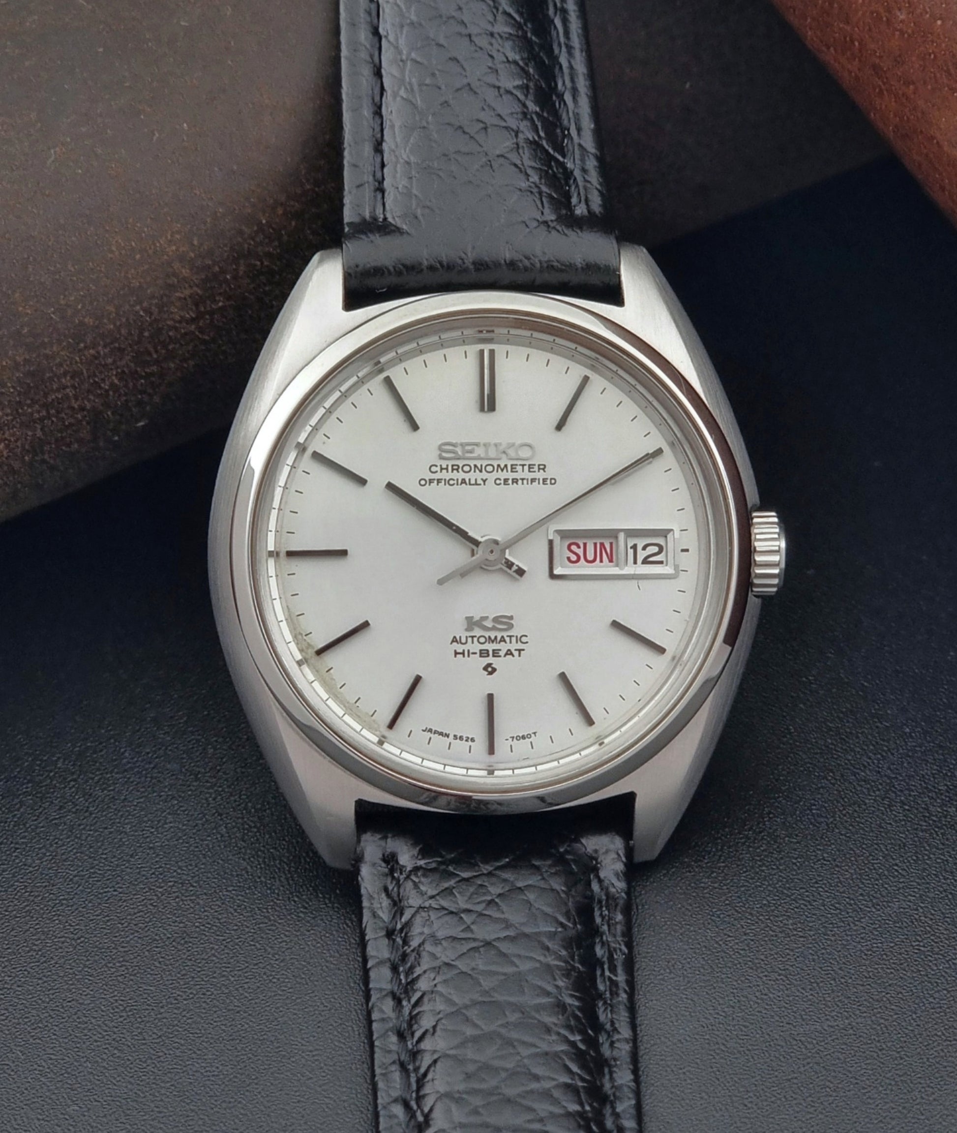 Vintage King Seiko 5626-7060 wristwatch with a silver case and black leather strap on a dark surface close up dial 