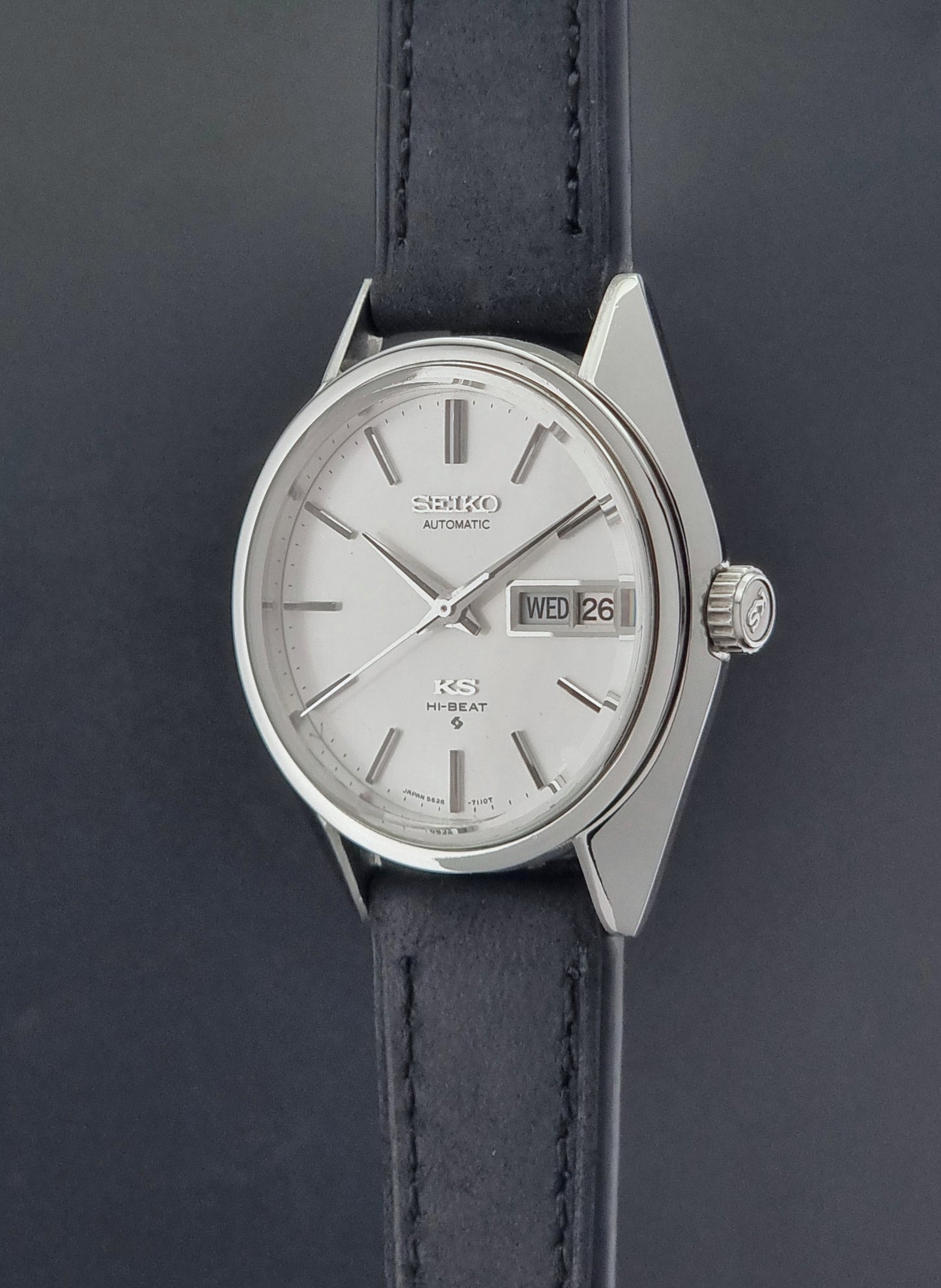 Vintage King Seiko 5626-7110 wristwatch with black leather strap on a gray background crown profile view