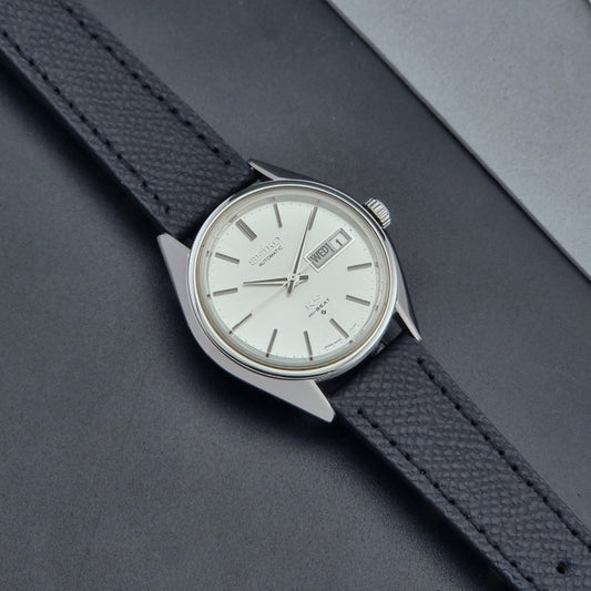 Vintage King Seiko Wristwatch 5626-7110 with a silver case and black strap on a dark gray background dial