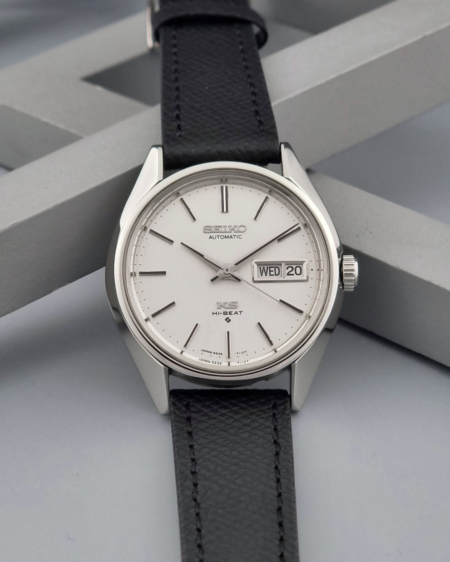 Vintage King Seiko 5626-7110 Wristwatch with a silver case and black strap on a dark gray background dial view