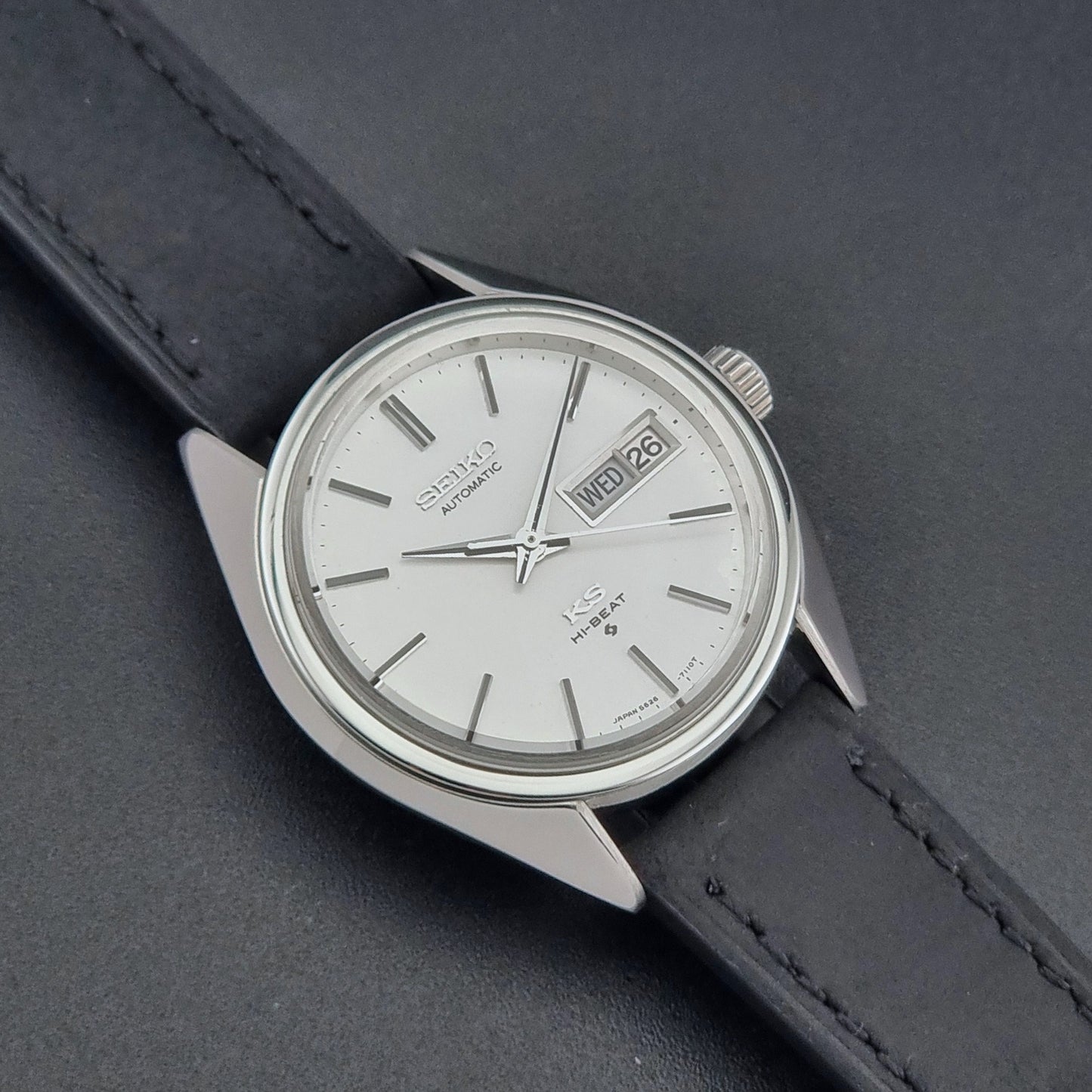 Vintage King Seiko 5626-7110 wristwatch with black leather strap on a gray background close up dial view