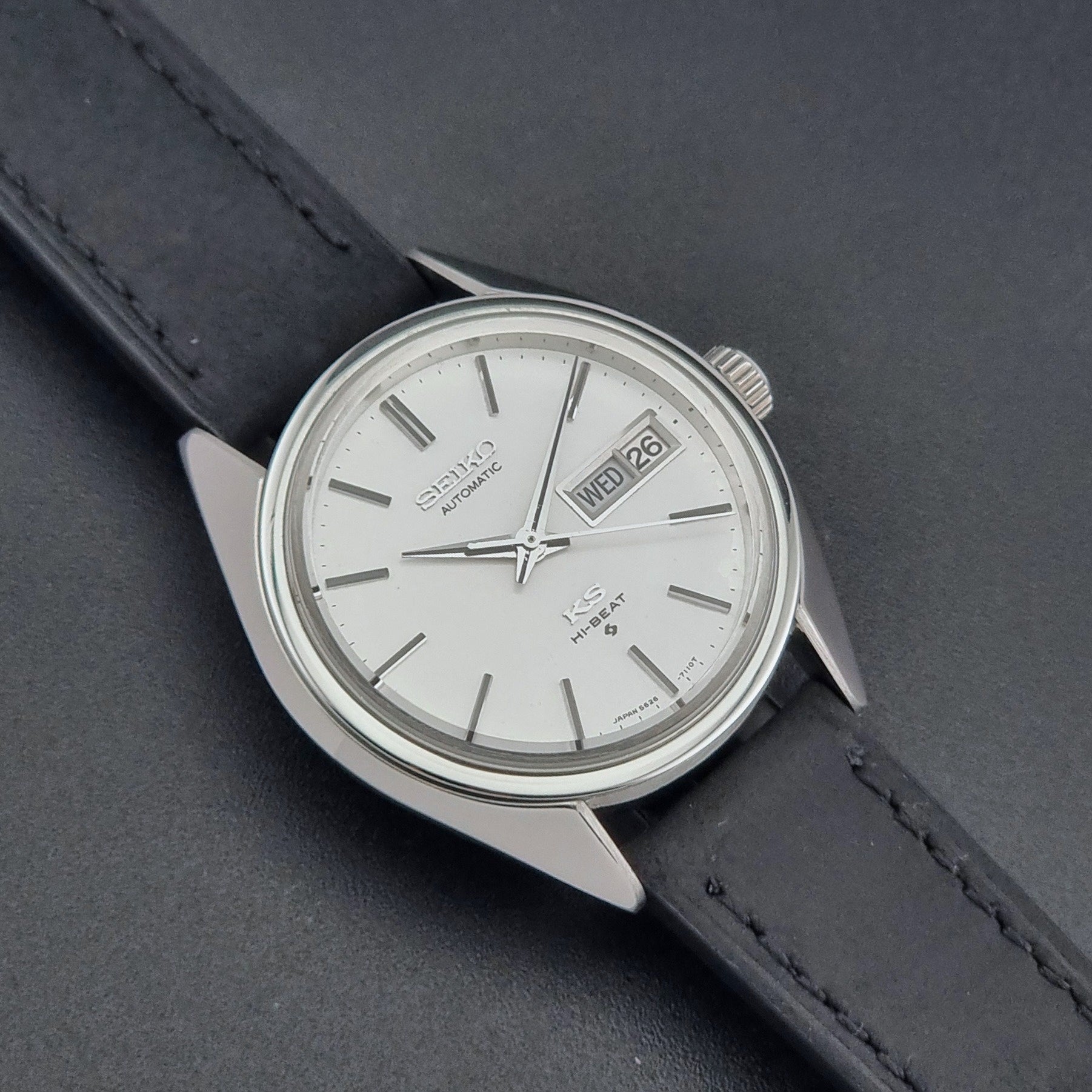 Vintage King Seiko 5626-7110 wristwatch with black leather strap on a gray background close up dial view