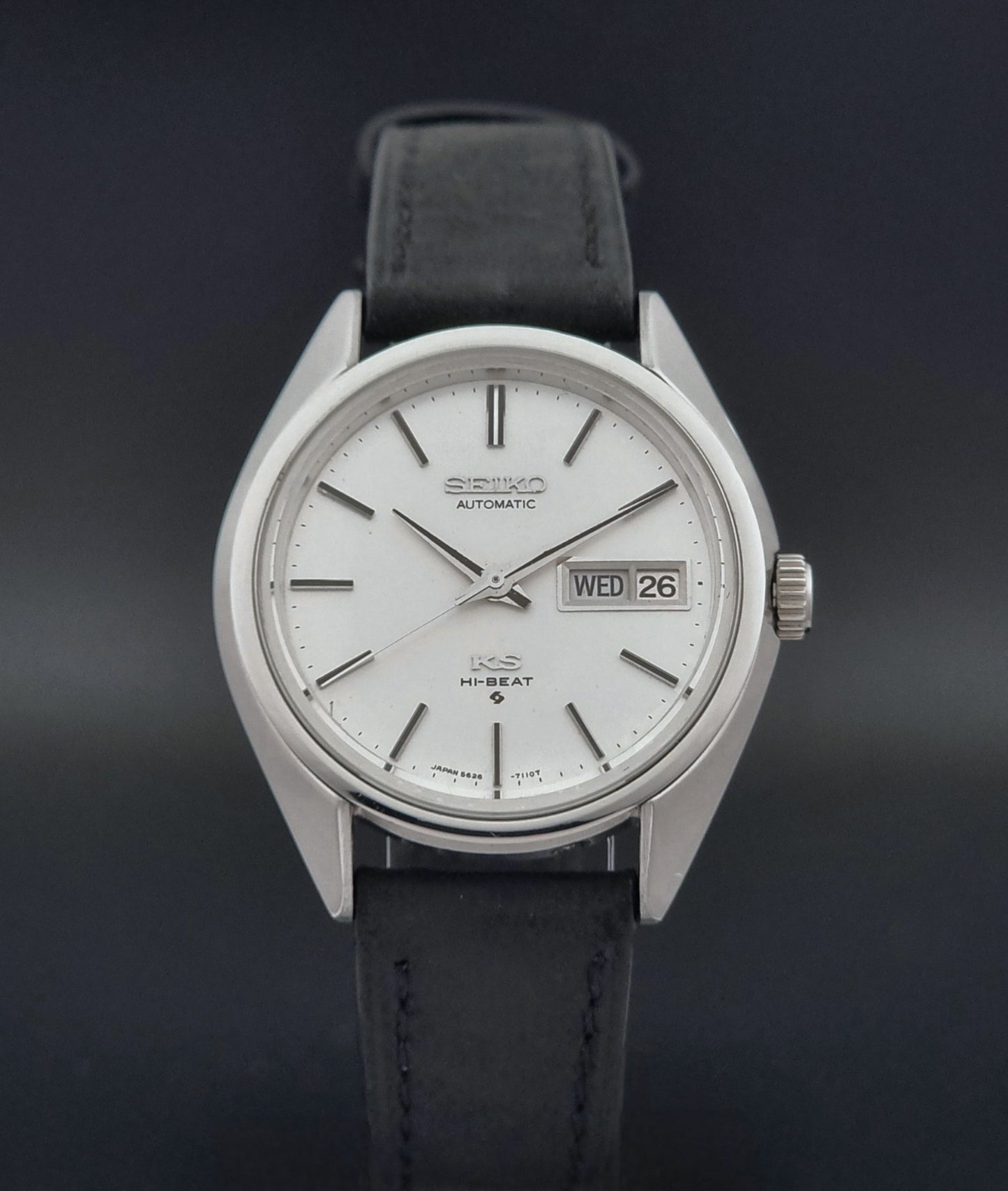 Vintage King Seiko 5626-7110 wristwatch with black leather strap on a gray background close dial view