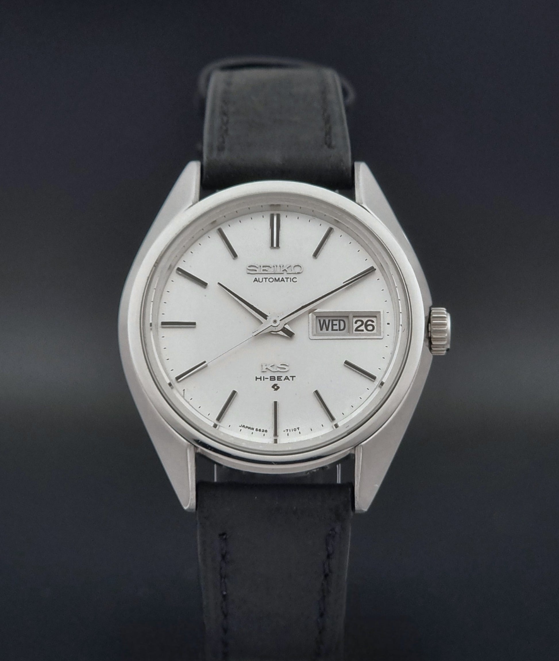 Vintage King Seiko 5626-7110 wristwatch with black leather strap on a gray background close dial view