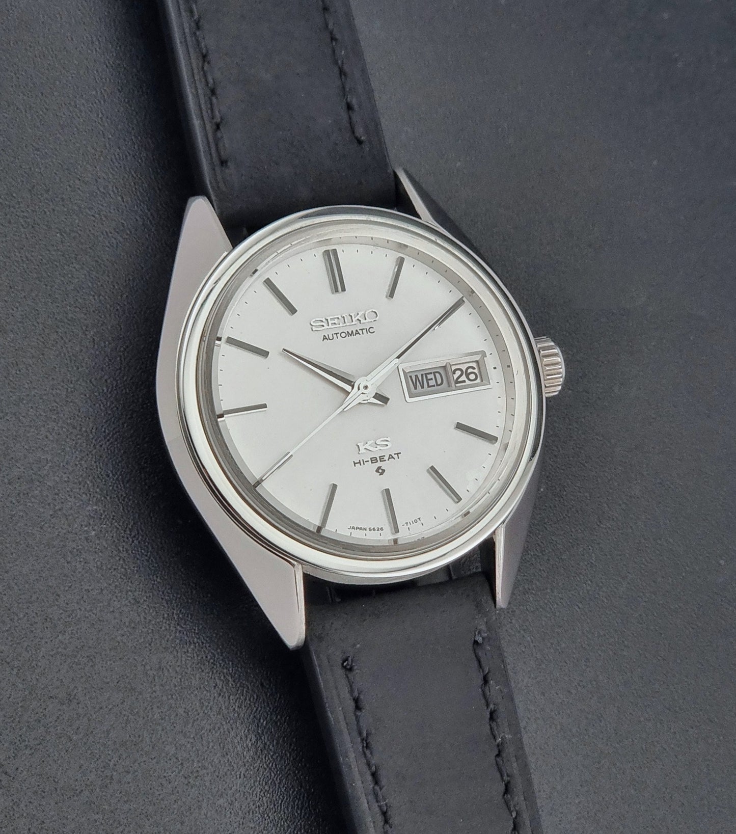 Vintage King Seiko 5626-7110 wristwatch with black leather strap on a gray background front view