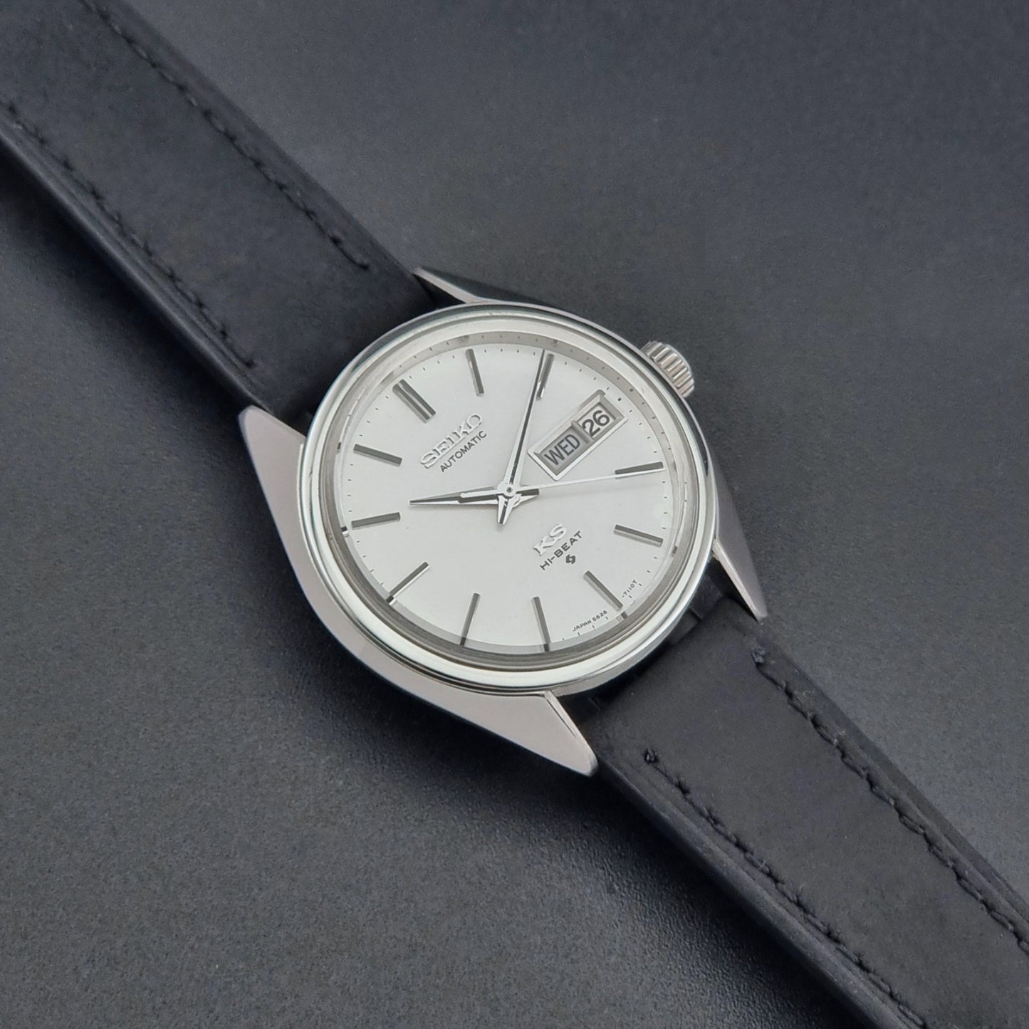Vintage King Seiko 5626-7110 wristwatch with black leather strap on a gray background dial