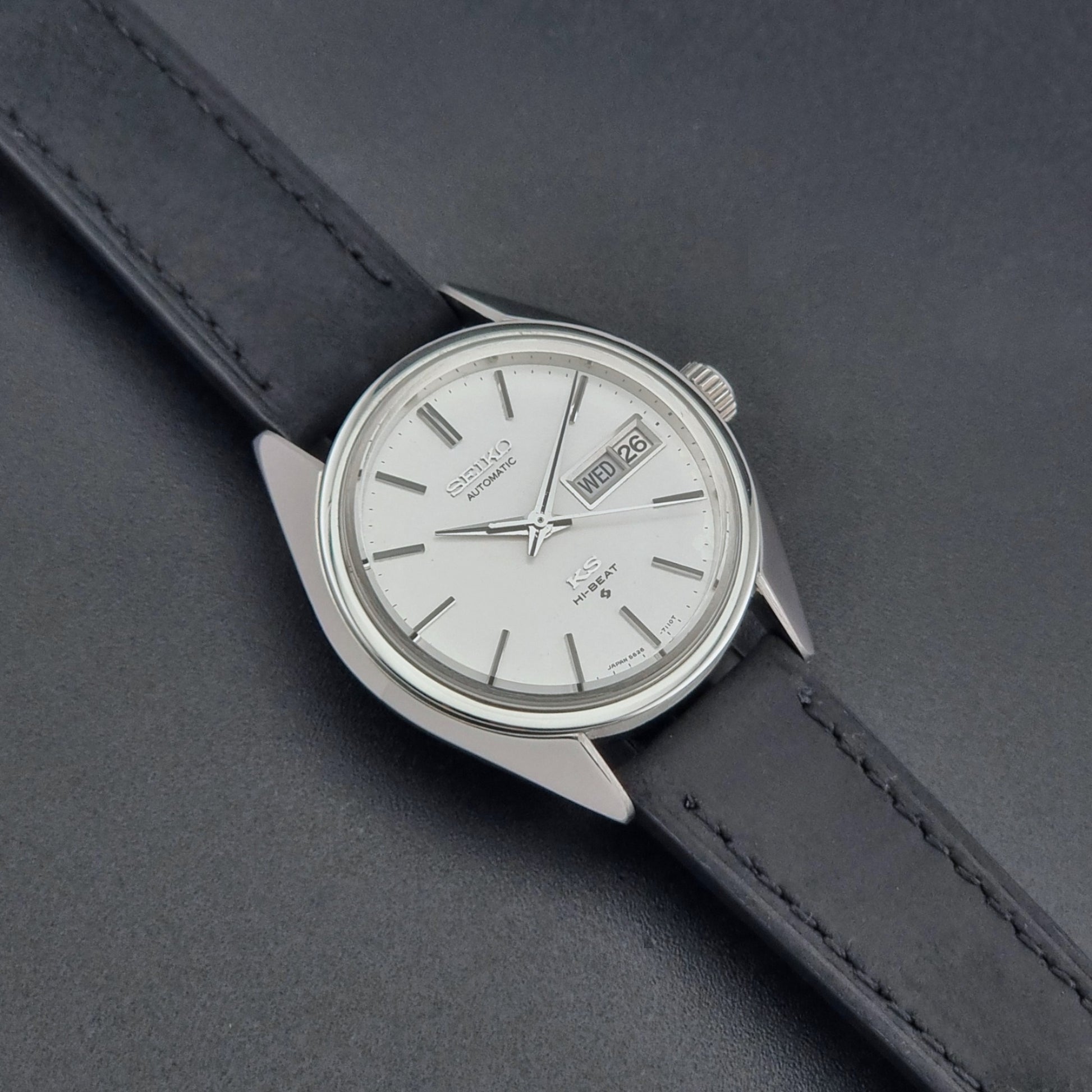 Vintage King Seiko 5626-7110 wristwatch with black leather strap on a gray background dial