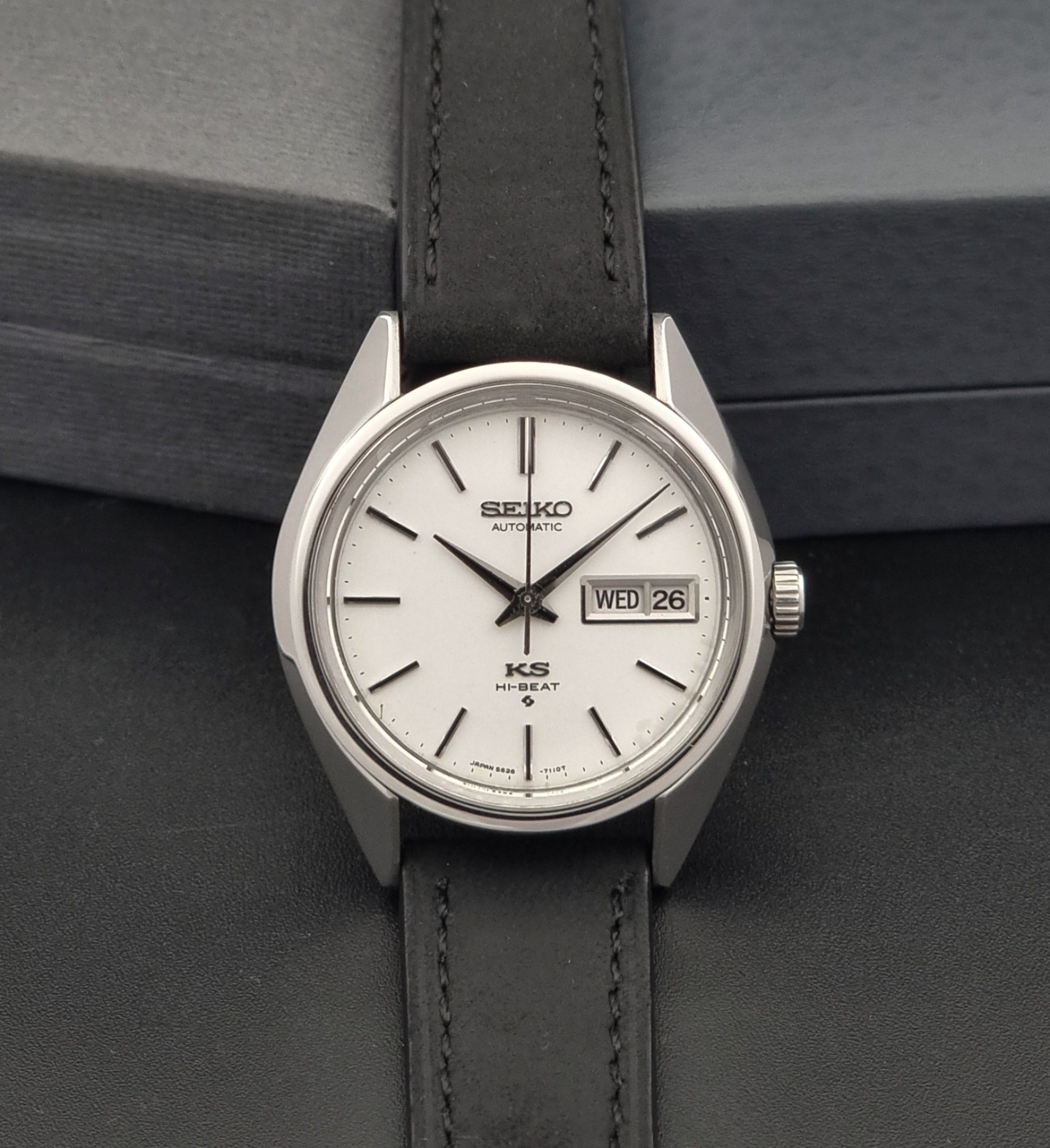 Vintage King Seiko 5626-7110 wristwatch with black leather strap on a gray background dial view