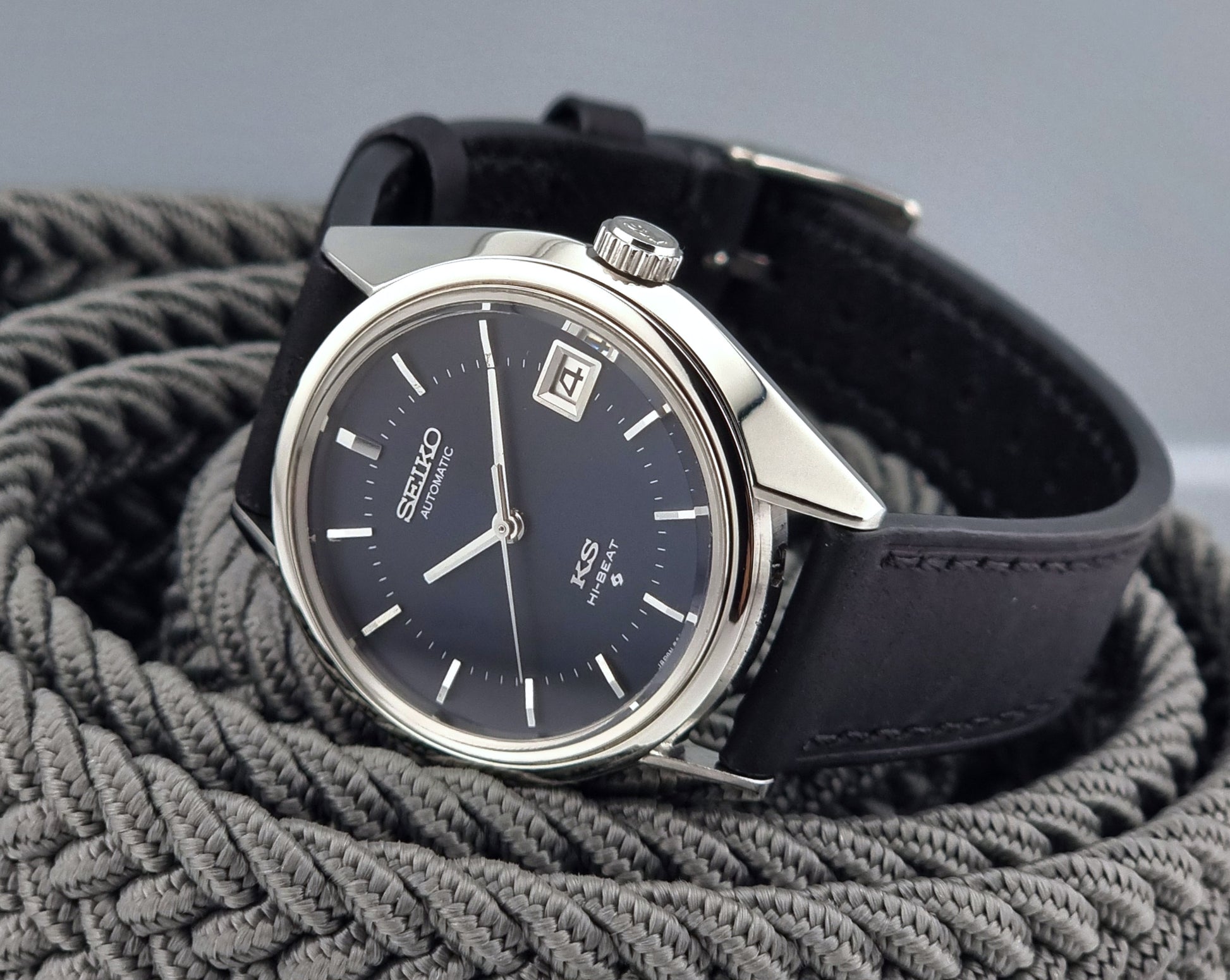 Vintage King Seiko watch with black strap on a textured gray surface