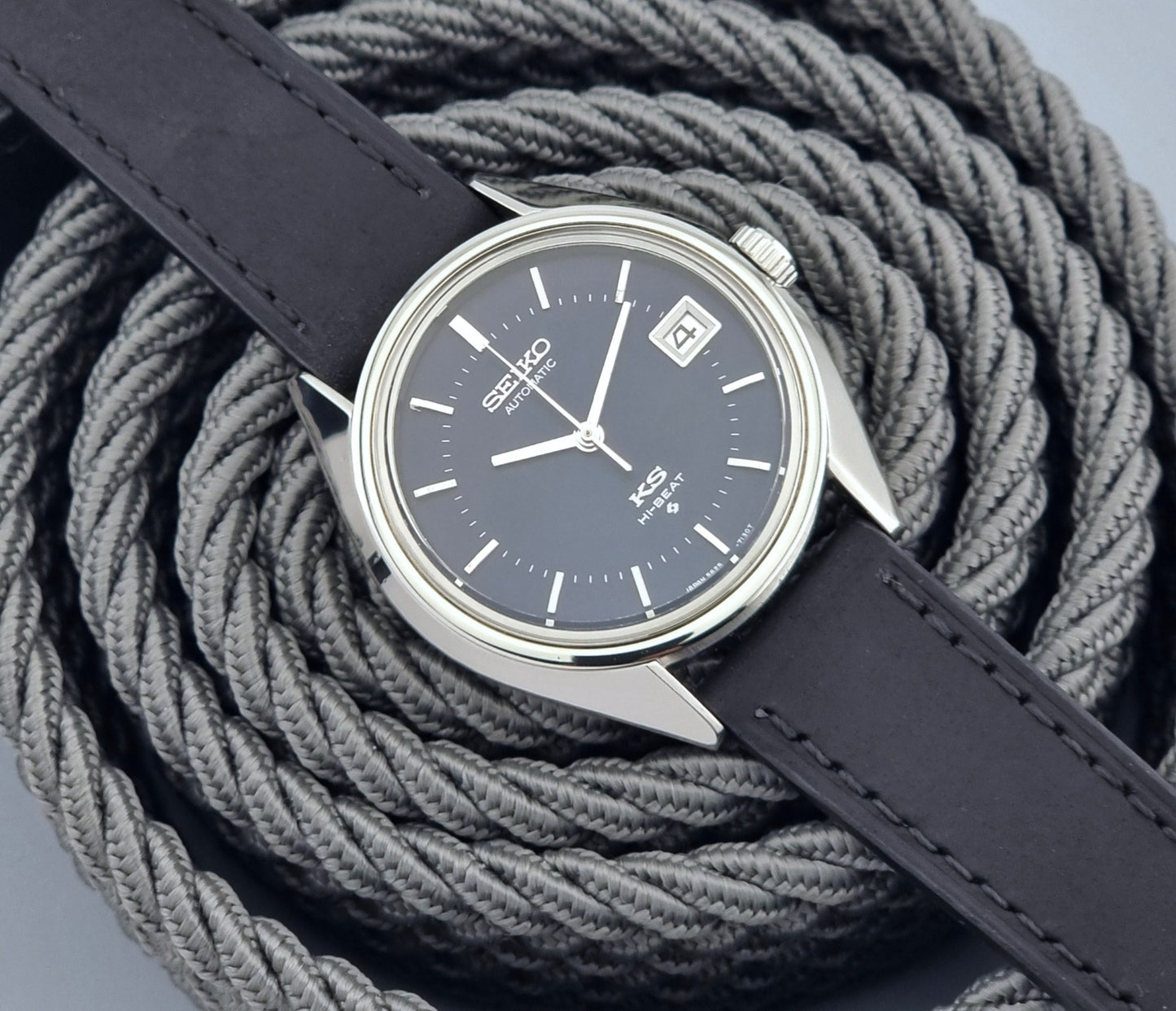 Vintage King Seiko watch with dark blue face and leather strap on a textured gray background